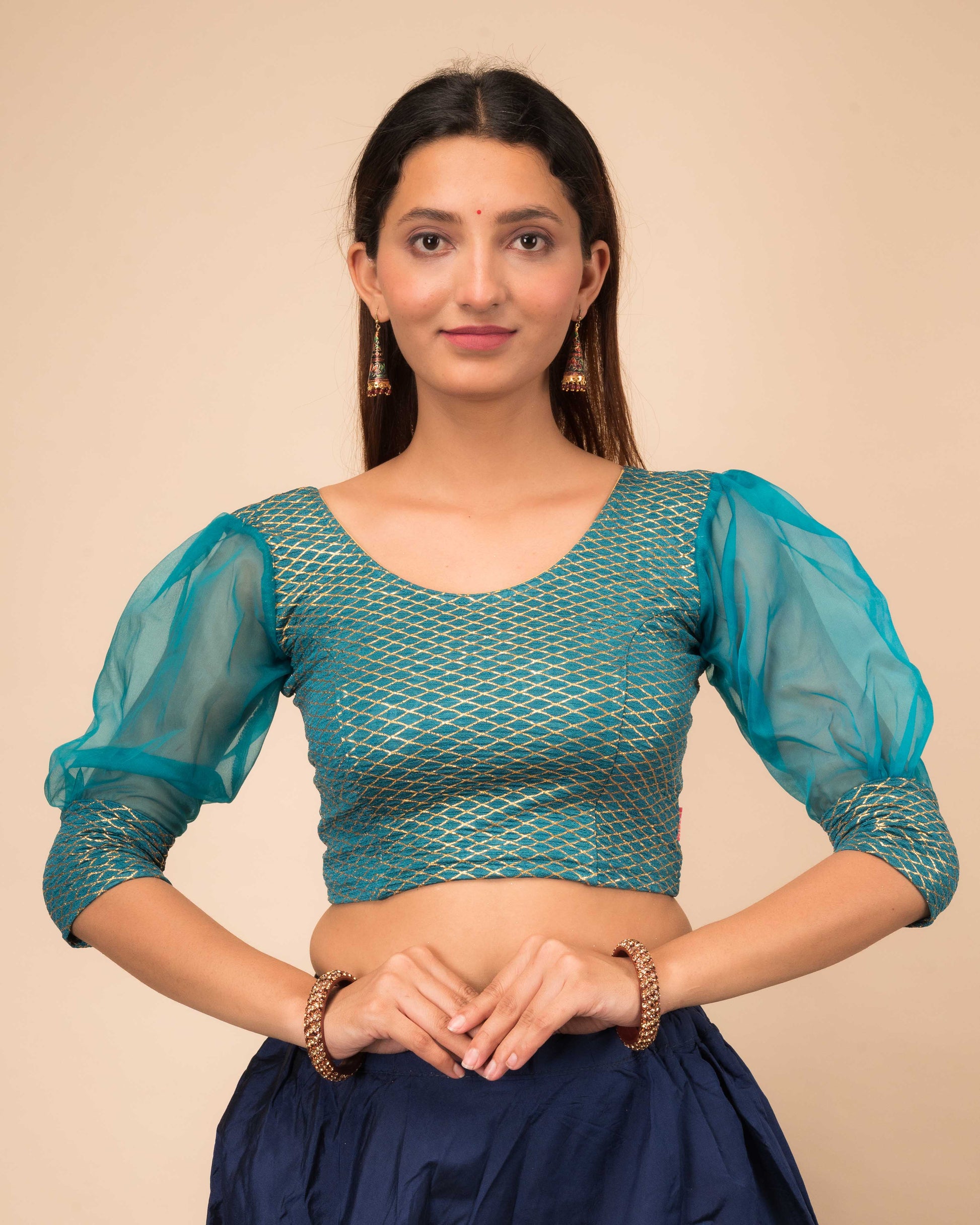 Model wearing a stretchable crushed organza blouse with long balloon sleeves, round neckline, and gold check pattern