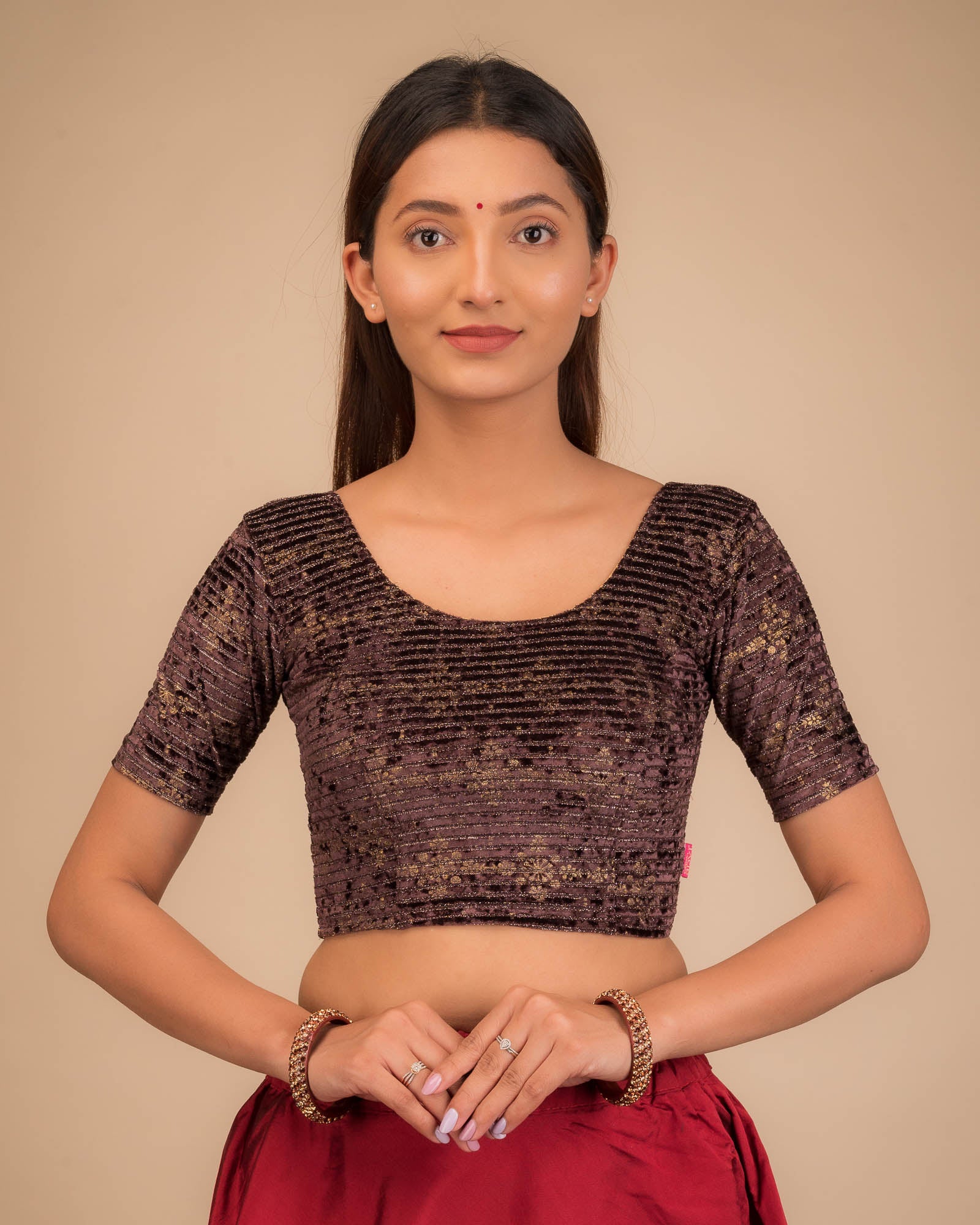 Model wearing a stretchable velvet blouse with elbow sleeves and round neckline.
