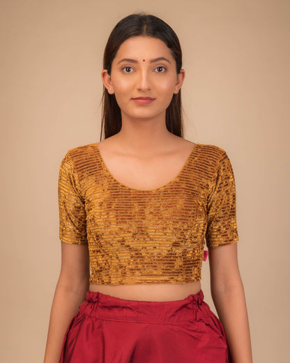 Model wearing a stretchable velvet blouse with elbow sleeves and round neckline.