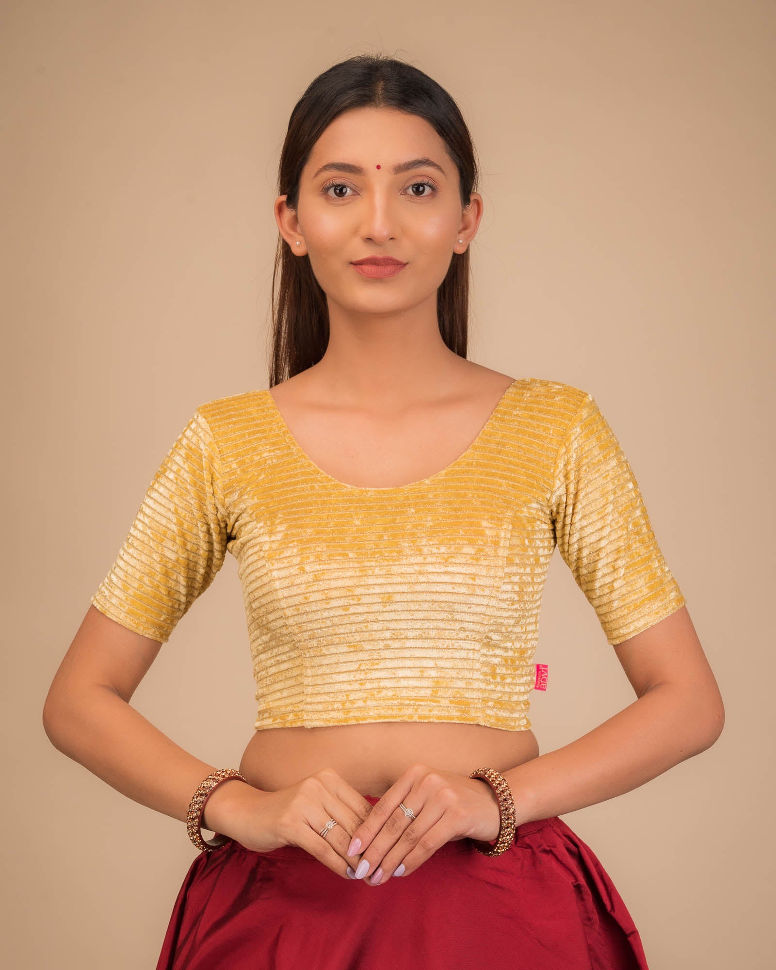 Model wearing a stretchable velvet blouse with elbow sleeves and round neckline.