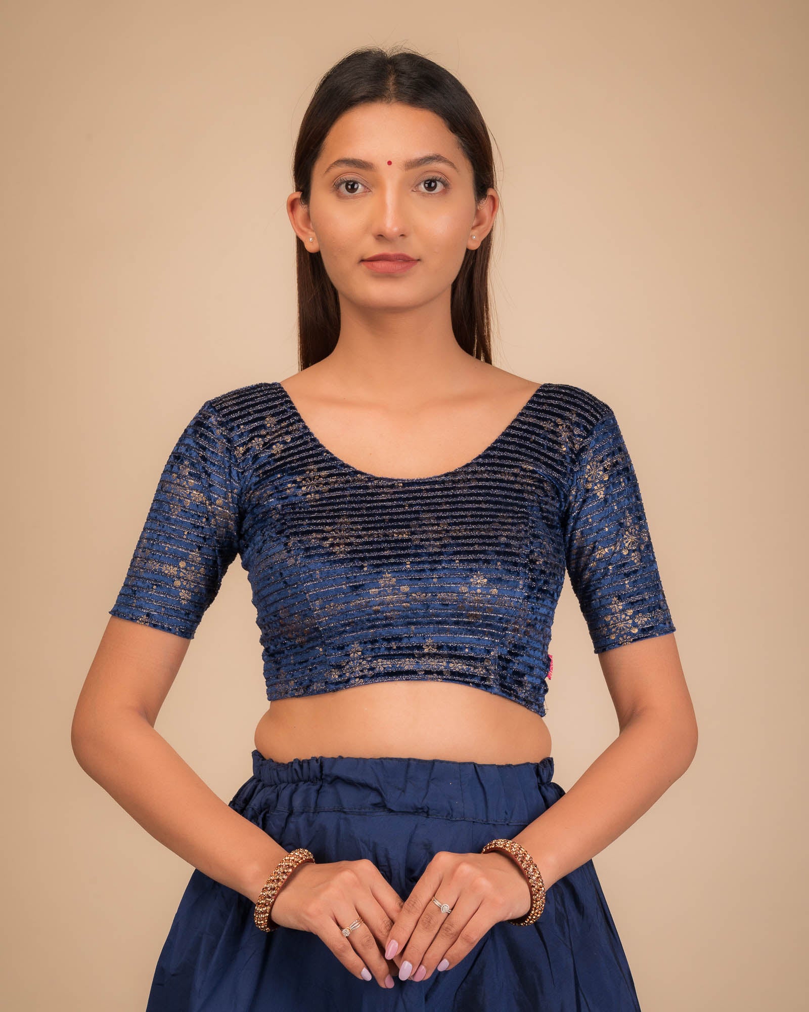 Model wearing a stretchable velvet blouse with elbow sleeves and round neckline.