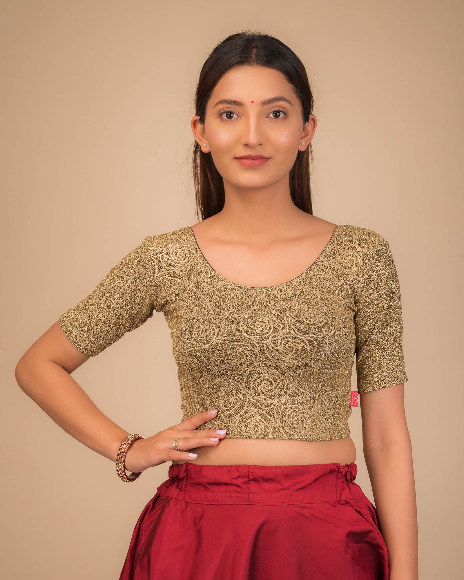 Model wearing a stretchable blouse with elbow sleeves and round neckline, featuring metallic emboss detailing.