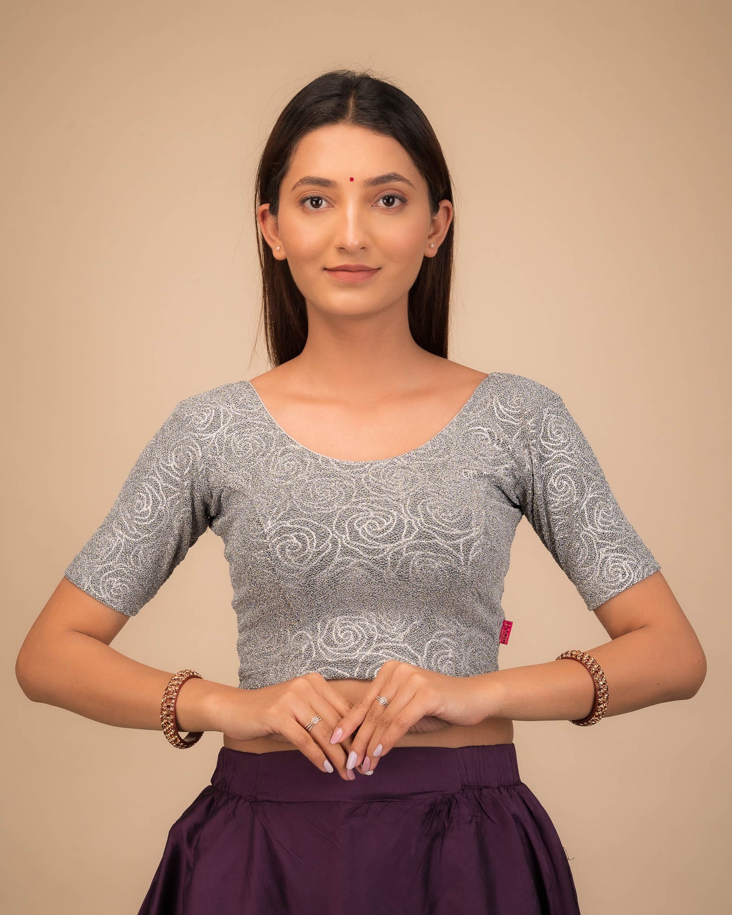 Model wearing a stretchable blouse with elbow sleeves and round neckline, featuring metallic emboss detailing.