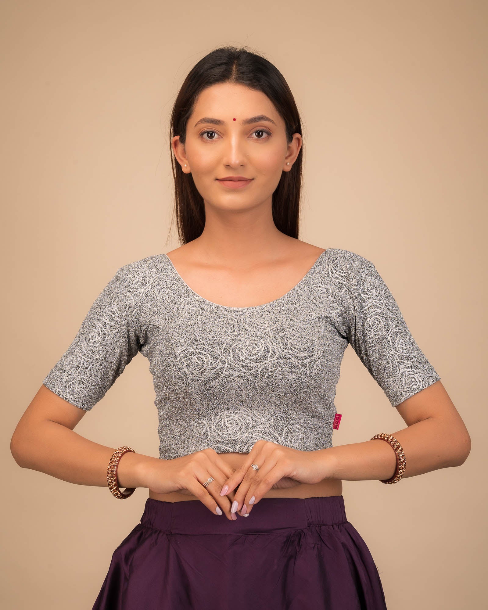 Model wearing a stretchable blouse with elbow sleeves and round neckline, featuring metallic emboss detailing.
