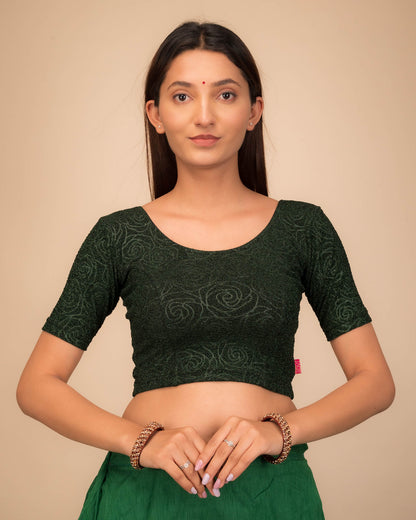 Model wearing a stretchable blouse with elbow sleeves and round neckline, featuring metallic emboss detailing.