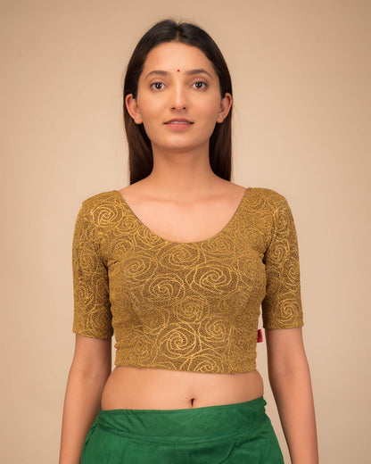 Model wearing a stretchable blouse with elbow sleeves and round neckline, featuring metallic emboss detailing.