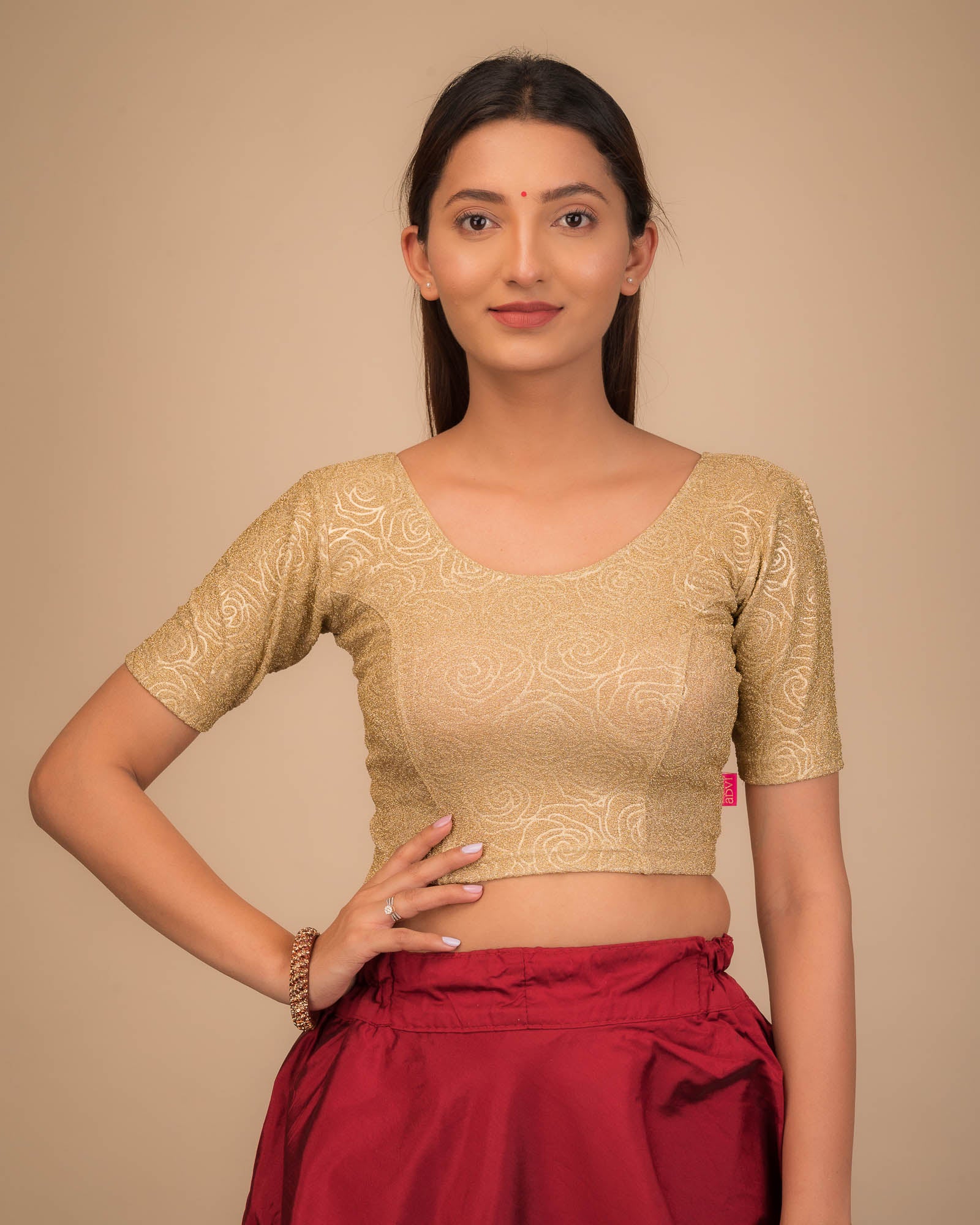 Model wearing a stretchable blouse with elbow sleeves and round neckline, featuring metallic emboss detailing.