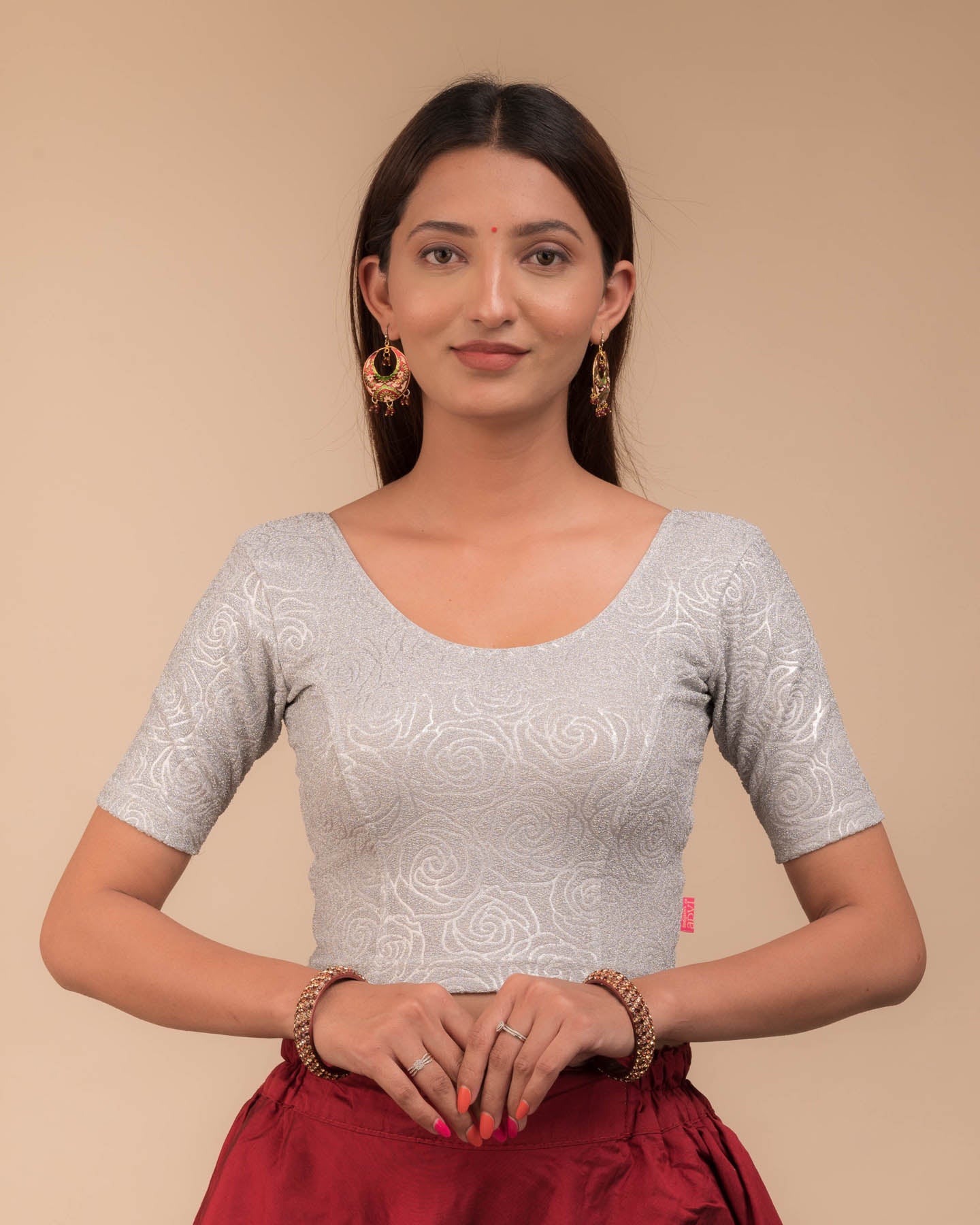 Model wearing a stretchable blouse with elbow sleeves and round neckline, featuring metallic emboss detailing.