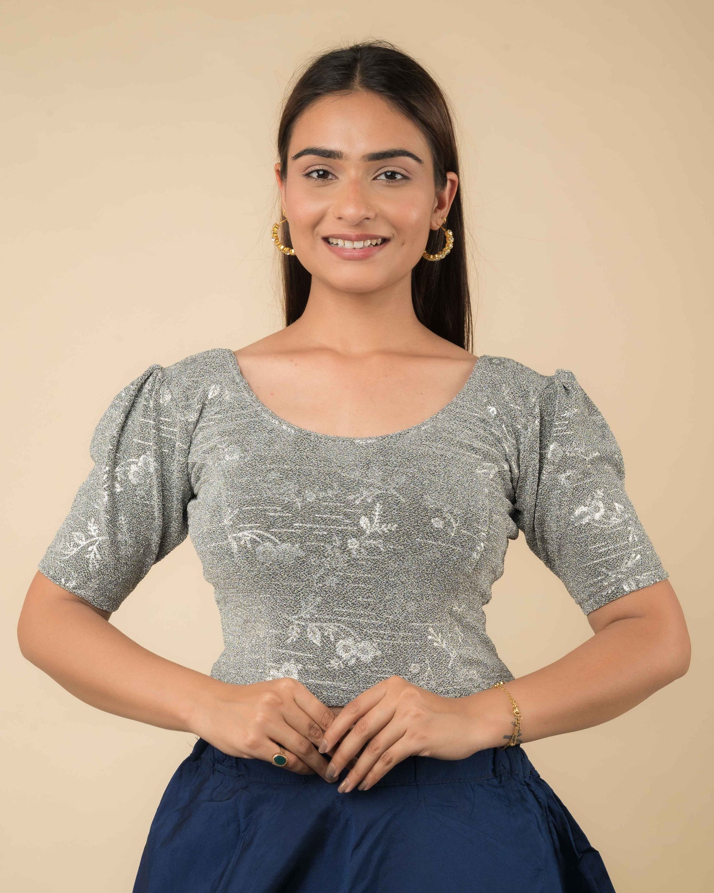 Model wearing metallic embossed blouse with puff elbow sleeves and round neckline, paired with saree.