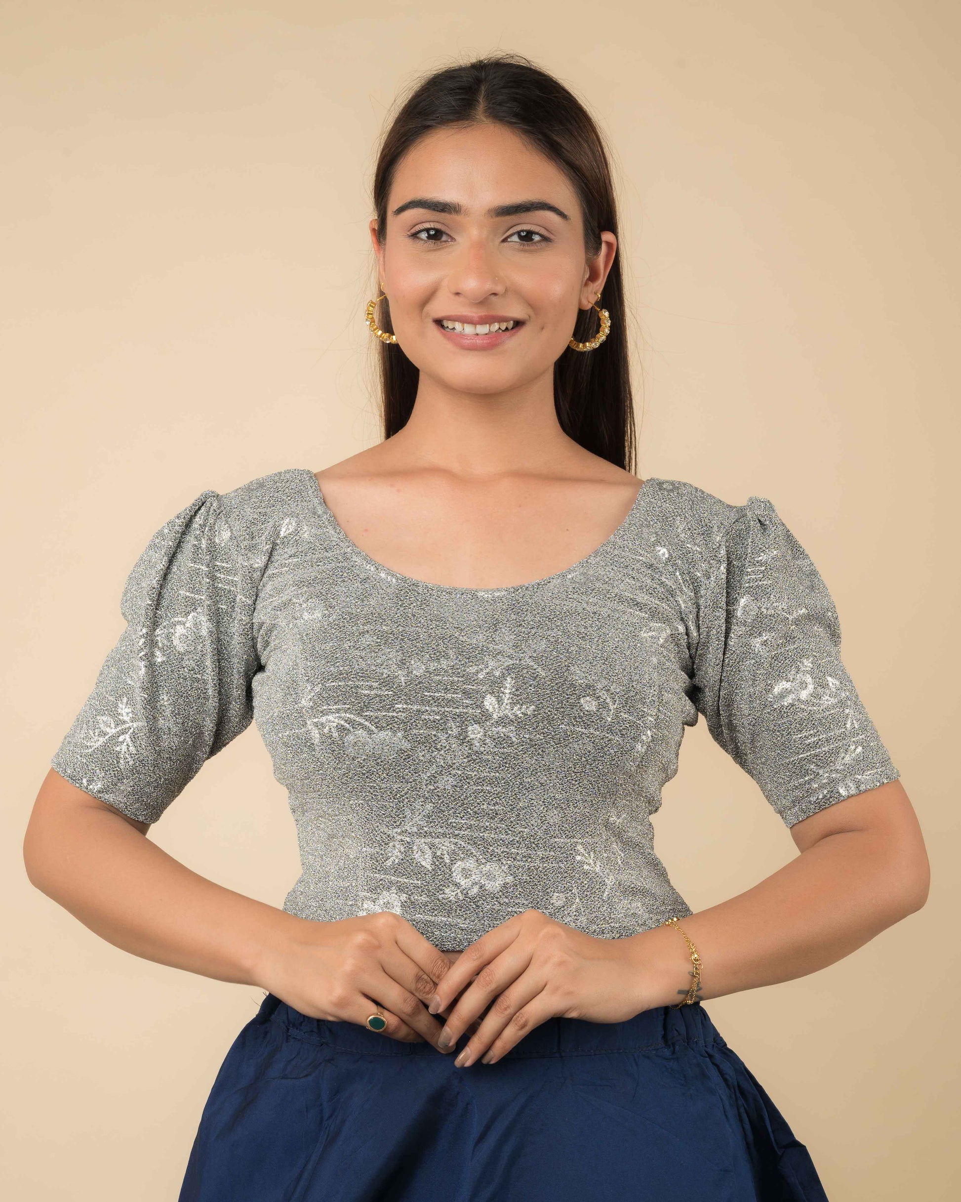 Model wearing metallic embossed blouse with puff elbow sleeves and round neckline, paired with saree.