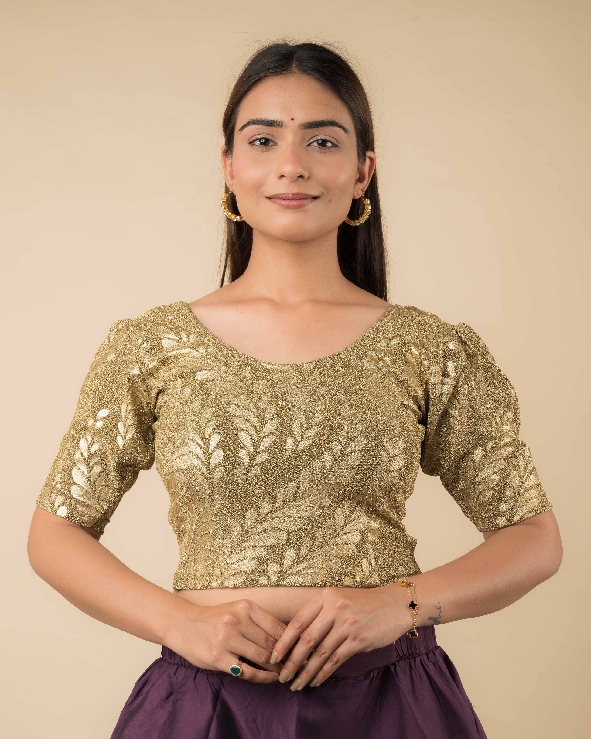 Model wearing metallic embossed blouse with puff elbow sleeves and round neckline, paired with saree.
