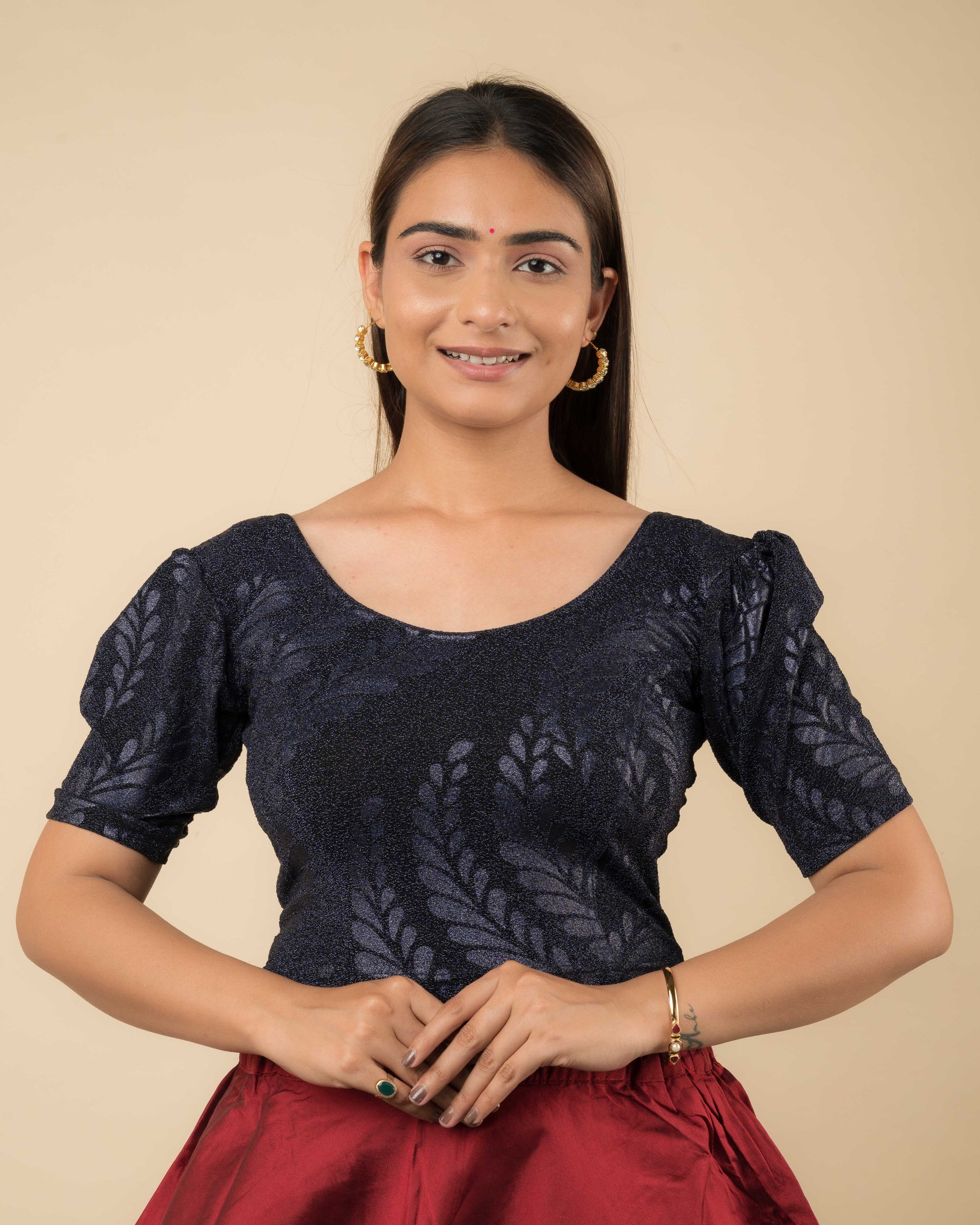 Model wearing bright gold metallic zari stretchable blouse with elbow sleeves and round neckline, featuring emboss pattern.