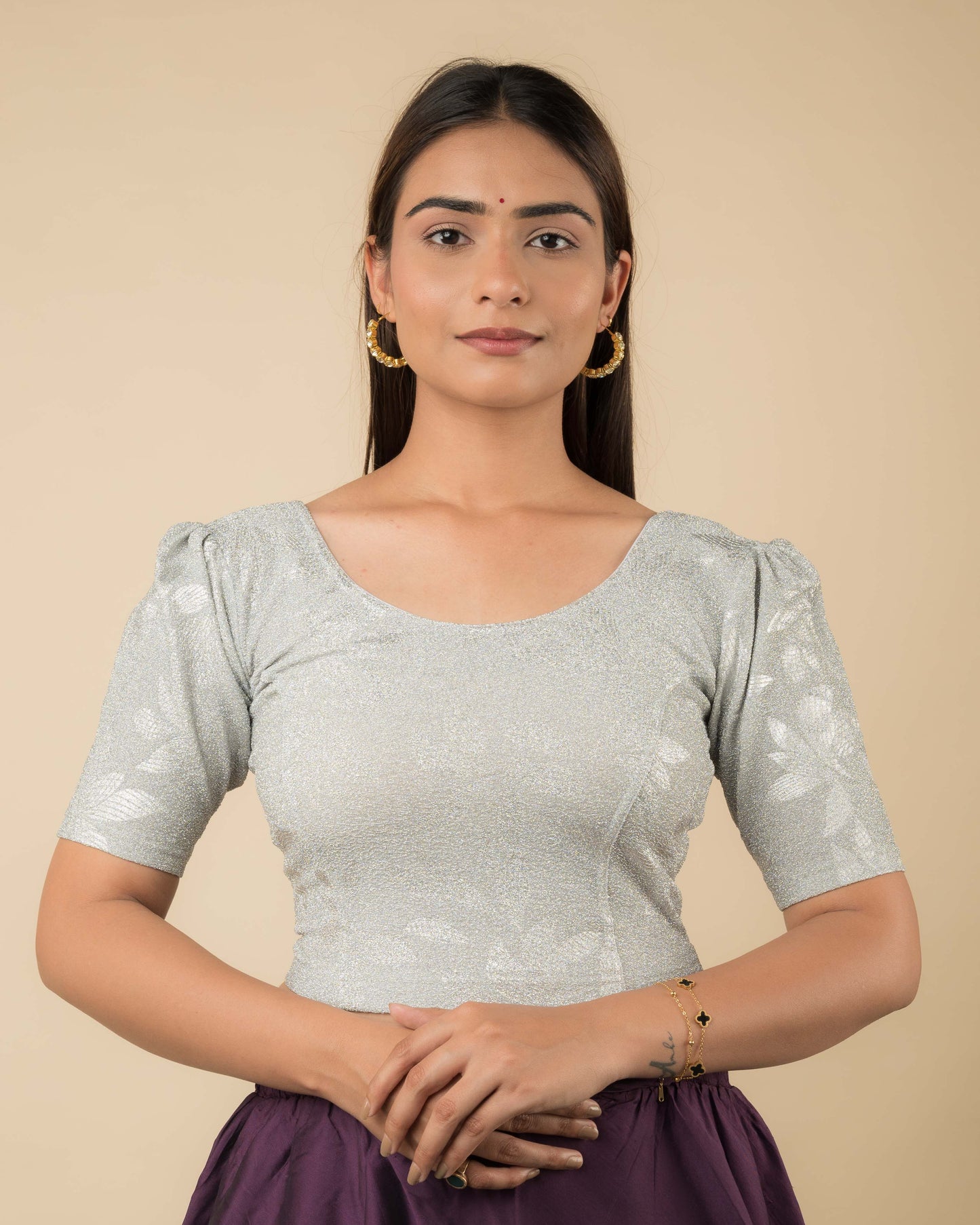 Model wearing metallic embossed blouse with puff elbow sleeves and round neckline, paired with saree.