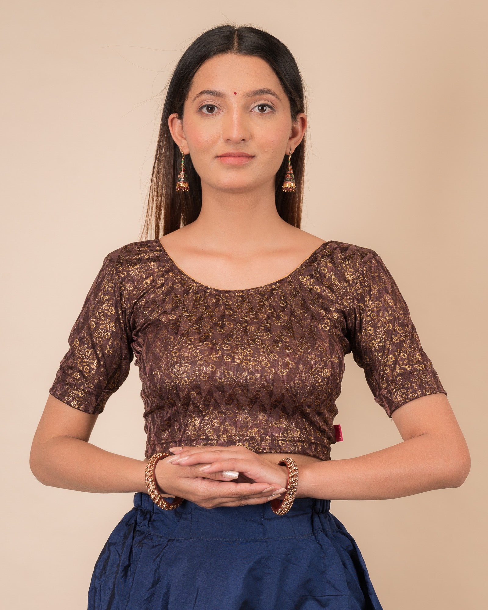 Model wearing a floral foil stretchable blouse with elbow sleeves, round neckline, and ruffle detail