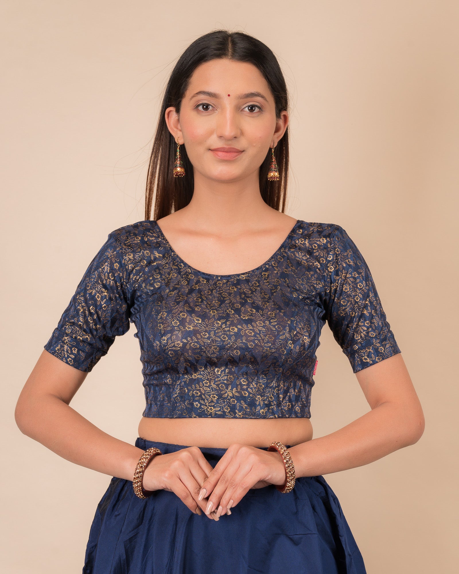 Model wearing a floral foil stretchable blouse with elbow sleeves, round neckline, and ruffle detail