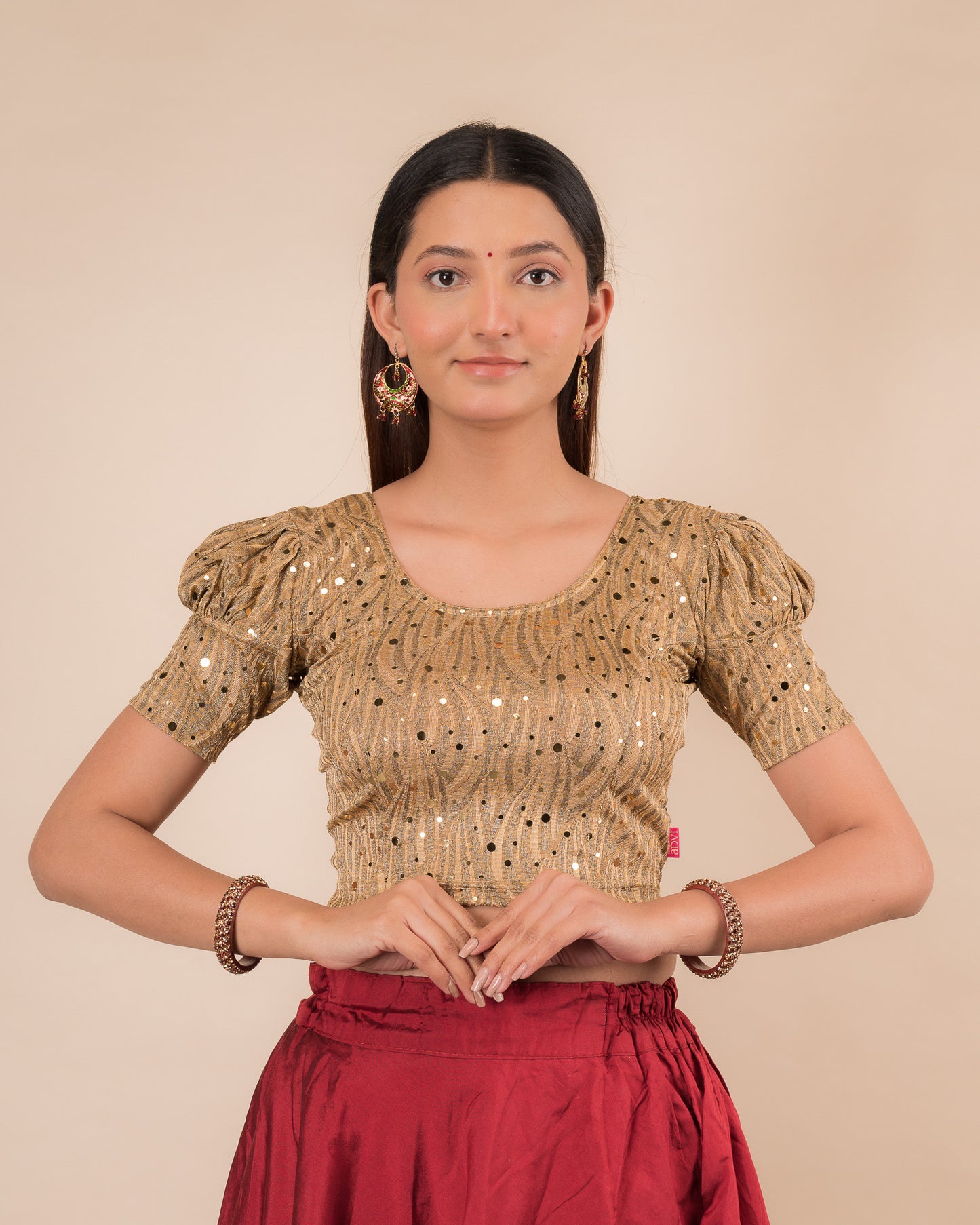 Model wearing a red stretchable blouse with gold mirror embellishments, puff sleeves, and round neckline