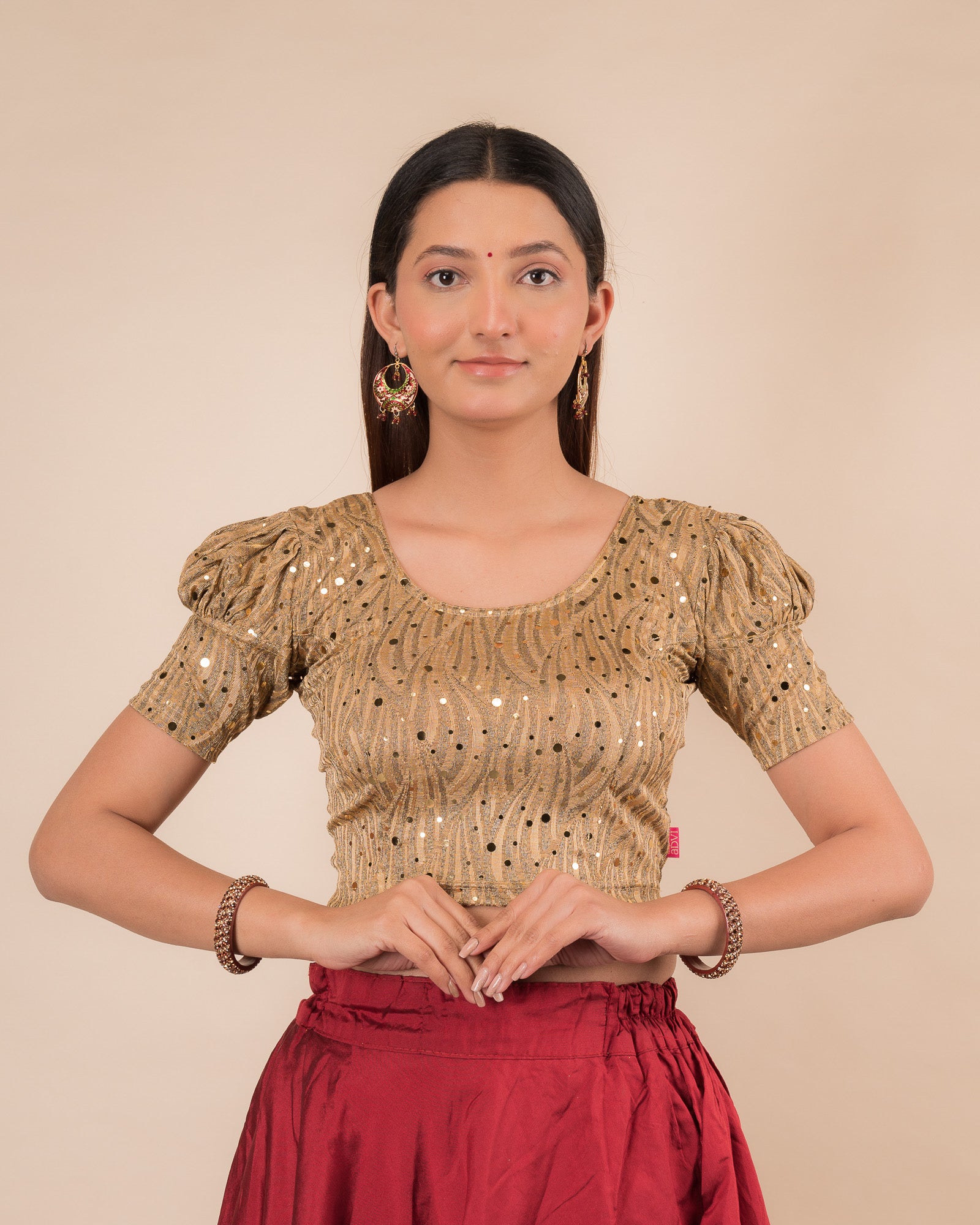 Model wearing a red stretchable blouse with gold mirror embellishments, puff sleeves, and round neckline