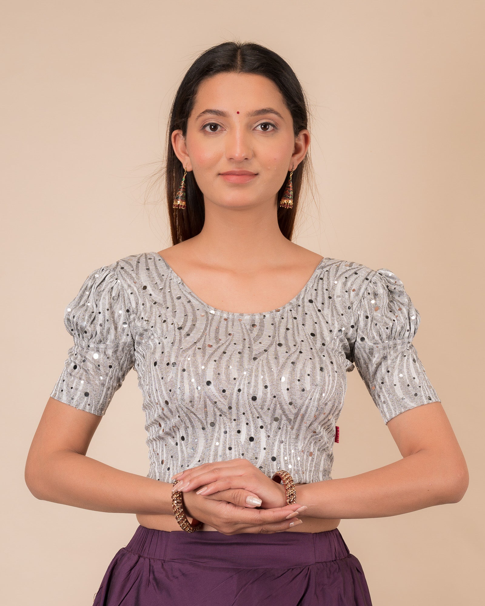 Model wearing a red stretchable blouse with gold mirror embellishments, puff sleeves, and round neckline