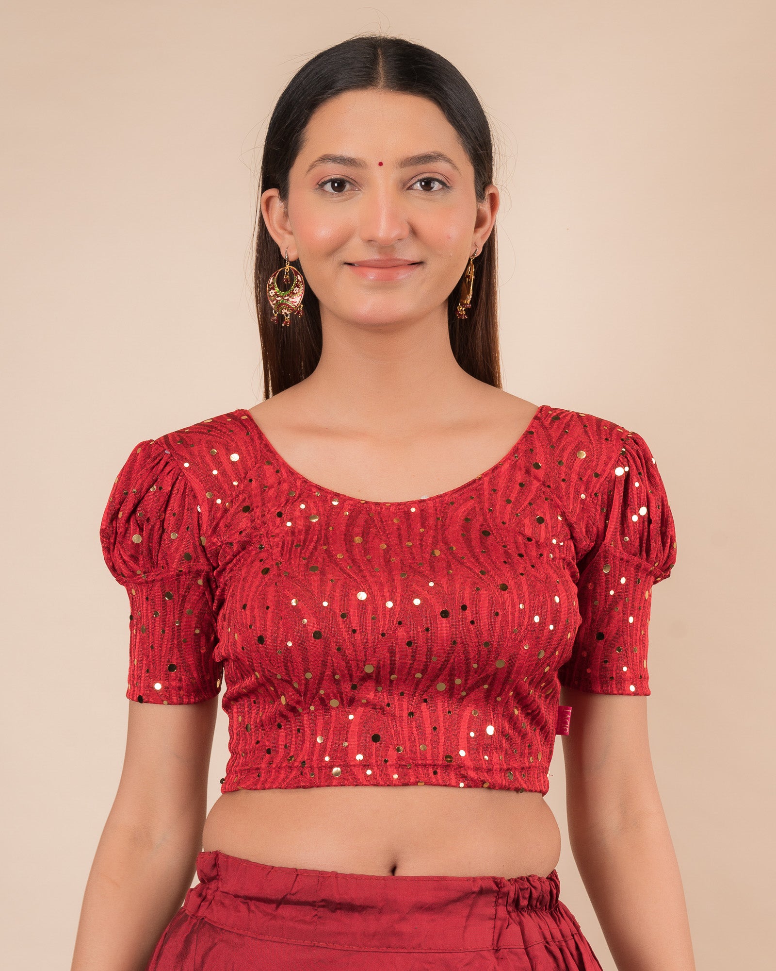 Model wearing a red stretchable blouse with gold mirror embellishments, puff sleeves, and round neckline