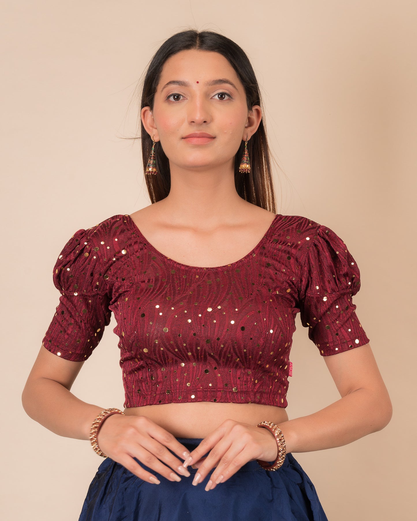 Model wearing a red stretchable blouse with gold mirror embellishments, puff sleeves, and round neckline