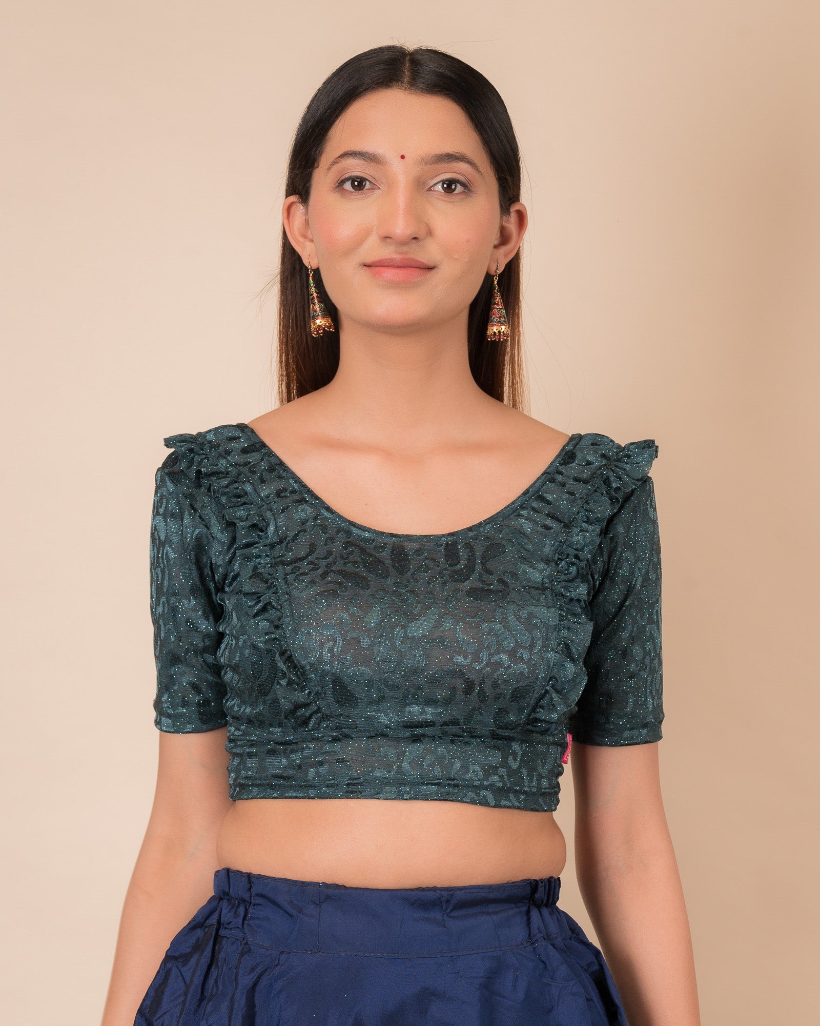 Model wearing an orange paisley paisley stretchable blouse with glitter, ruffled shoulders, elbow sleeves, and round neckline