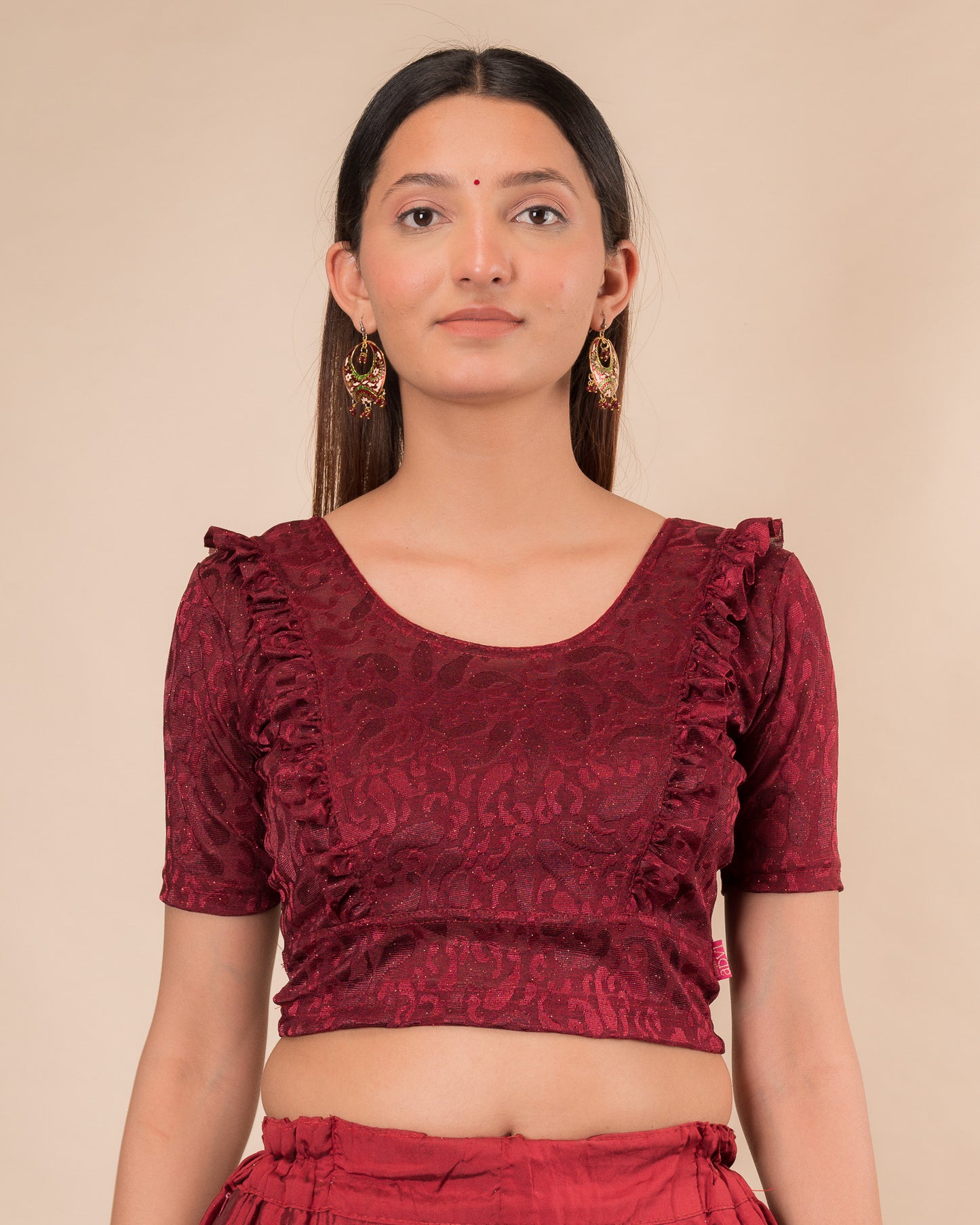 Model wearing an orange paisley paisley stretchable blouse with glitter, ruffled shoulders, elbow sleeves, and round neckline