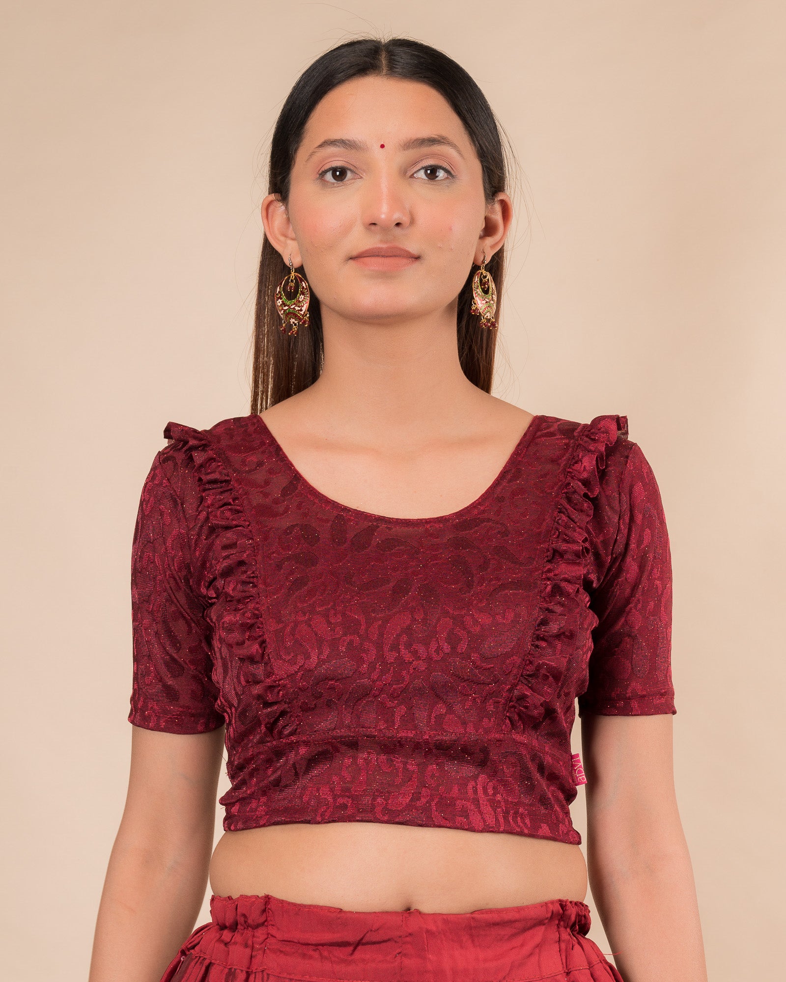 Model wearing an orange paisley paisley stretchable blouse with glitter, ruffled shoulders, elbow sleeves, and round neckline