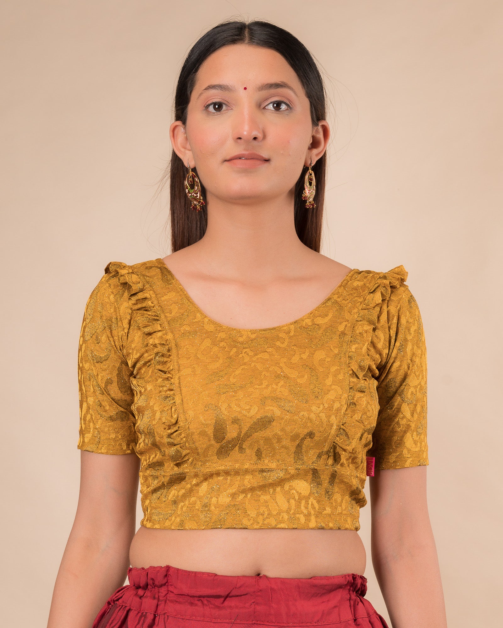Model wearing an orange paisley paisley stretchable blouse with glitter, ruffled shoulders, elbow sleeves, and round neckline