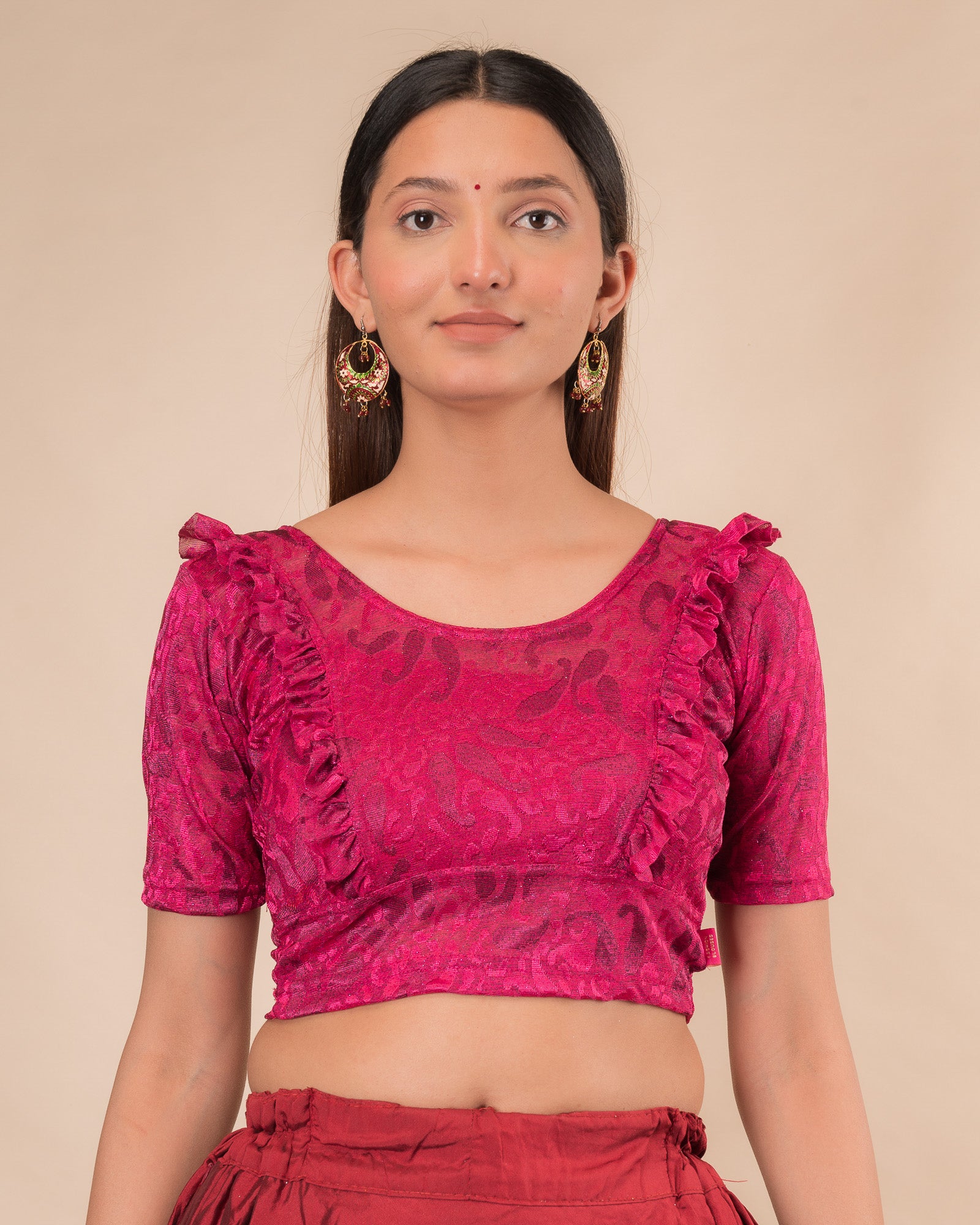 Model wearing an orange paisley paisley stretchable blouse with glitter, ruffled shoulders, elbow sleeves, and round neckline