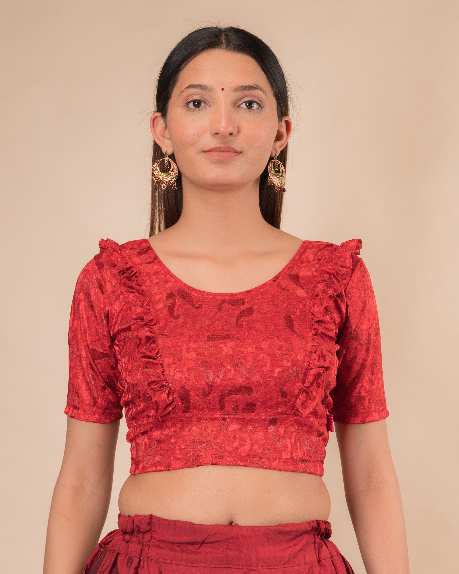 Model wearing an orange paisley paisley stretchable blouse with glitter, ruffled shoulders, elbow sleeves, and round neckline
