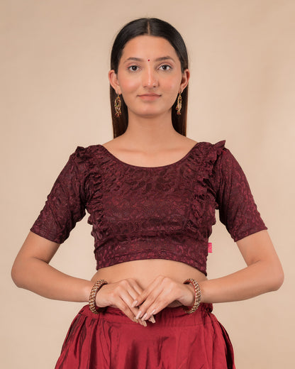 Model wearing an orange paisley paisley stretchable blouse with glitter, ruffled shoulders, elbow sleeves, and round neckline