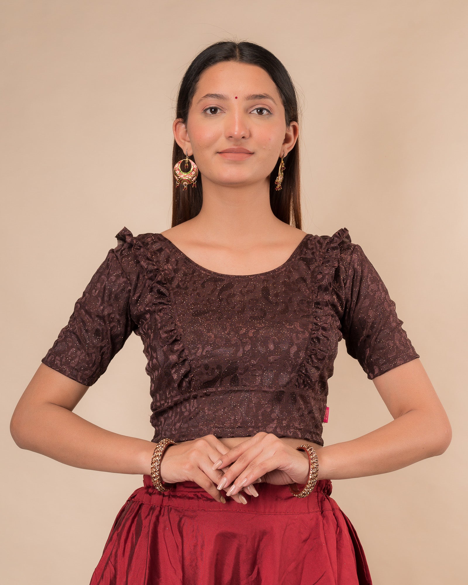 Model wearing an orange paisley paisley stretchable blouse with glitter, ruffled shoulders, elbow sleeves, and round neckline