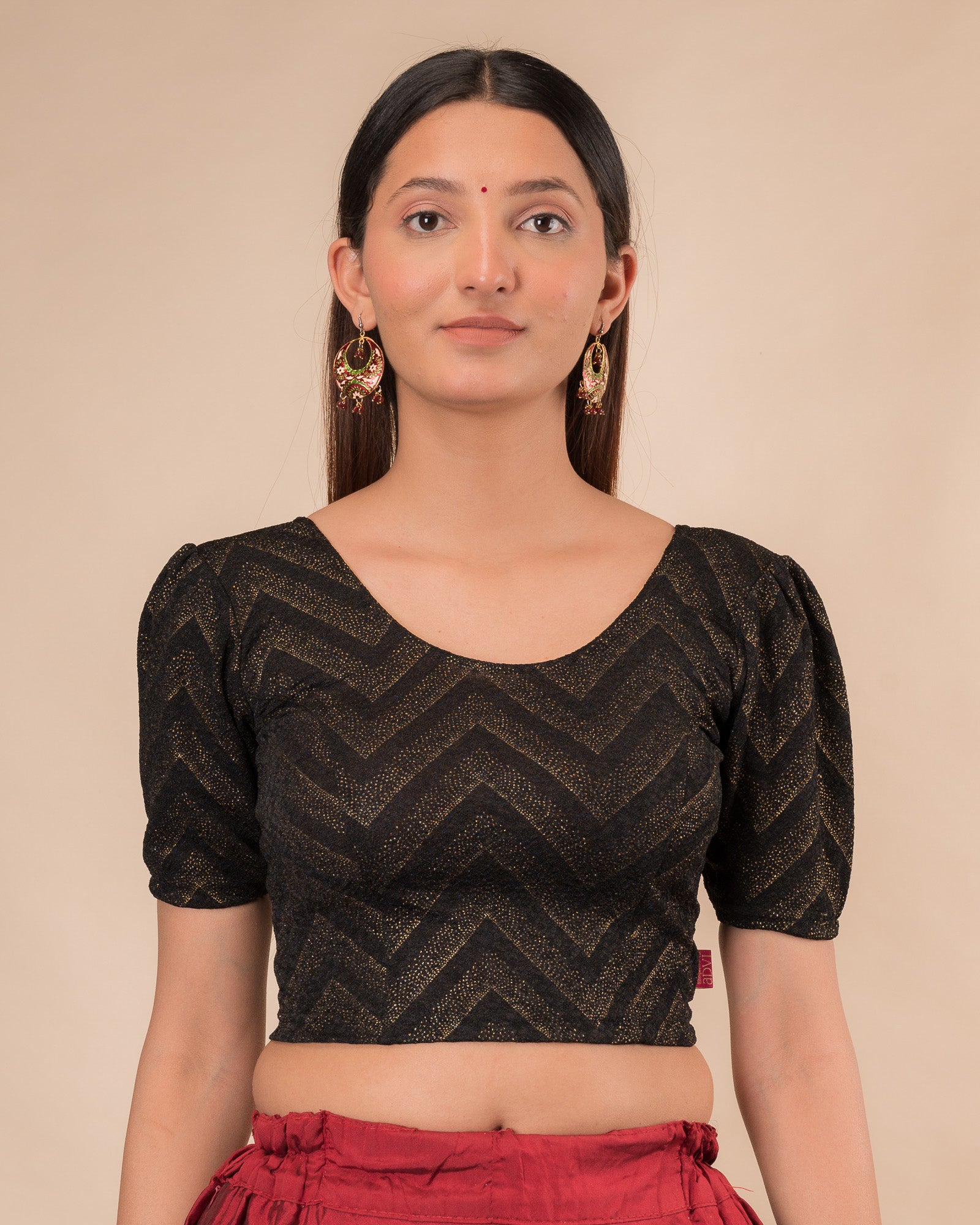 Model wearing an orange paisley paisley stretchable blouse with glitter, ruffled shoulders, elbow sleeves, and round neckline