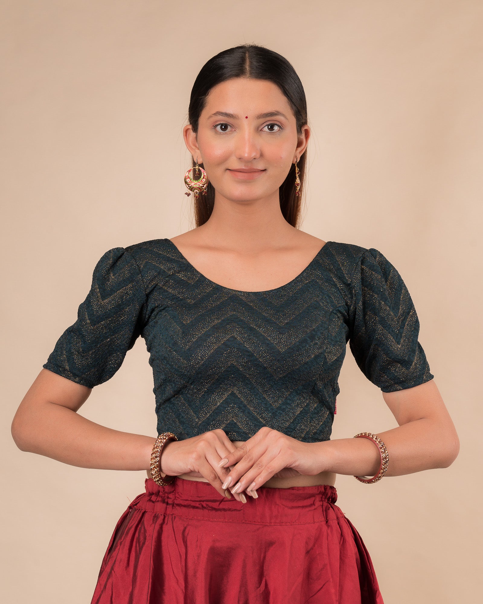 Model wearing an orange paisley paisley stretchable blouse with glitter, ruffled shoulders, elbow sleeves, and round neckline