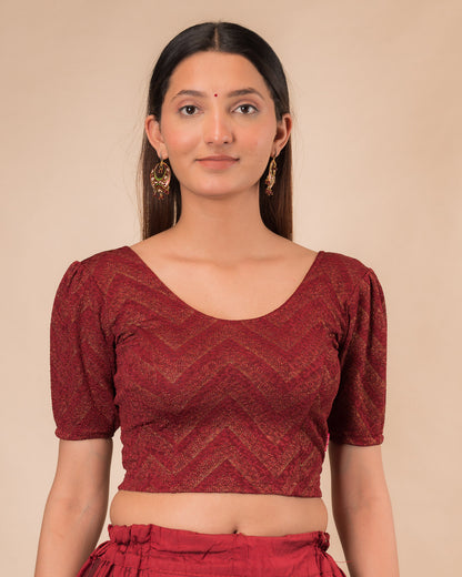 Model wearing an orange paisley paisley stretchable blouse with glitter, ruffled shoulders, elbow sleeves, and round neckline