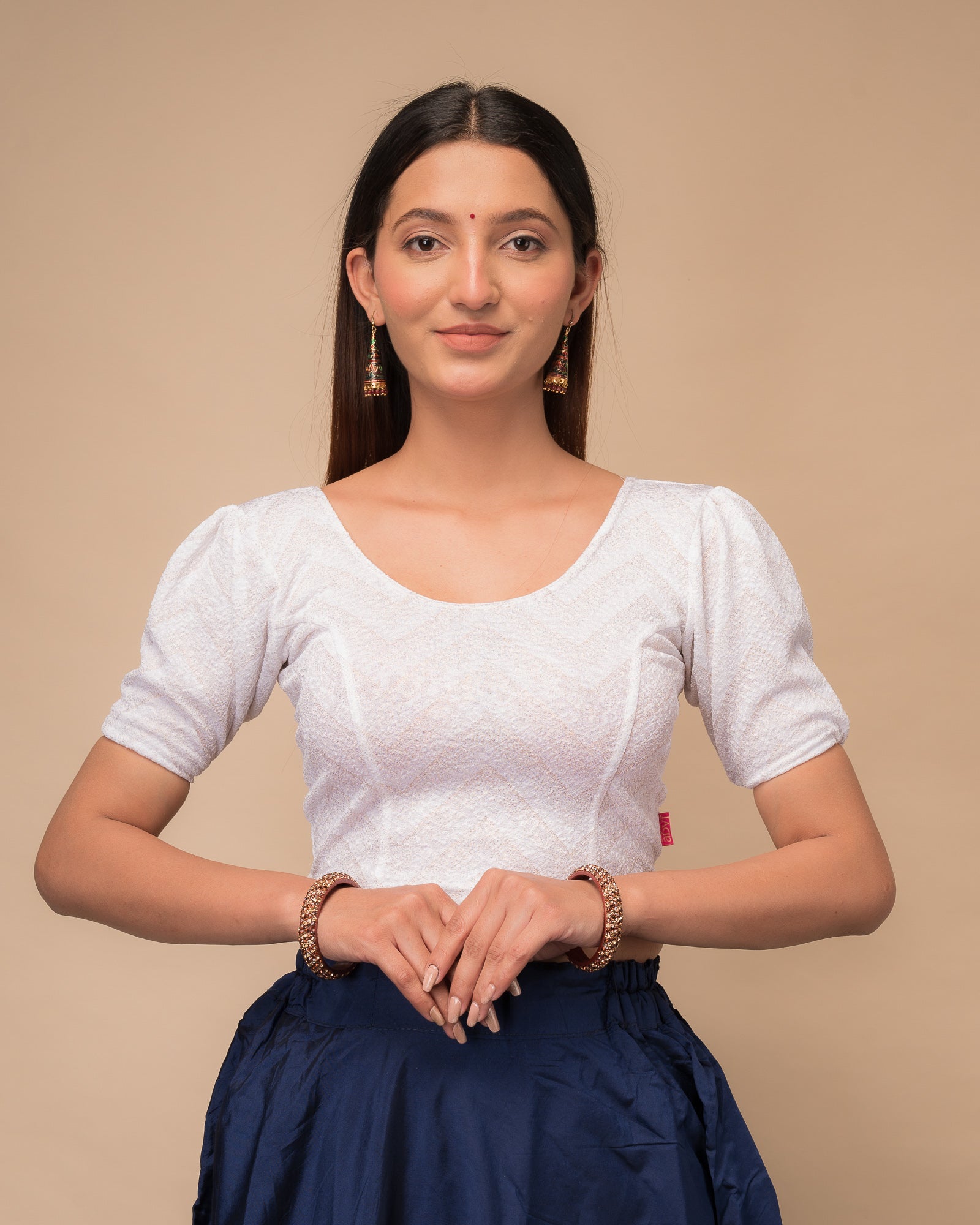  Model wearing an orange paisley paisley stretchable blouse with glitter, ruffled shoulders, elbow sleeves, and round neckline