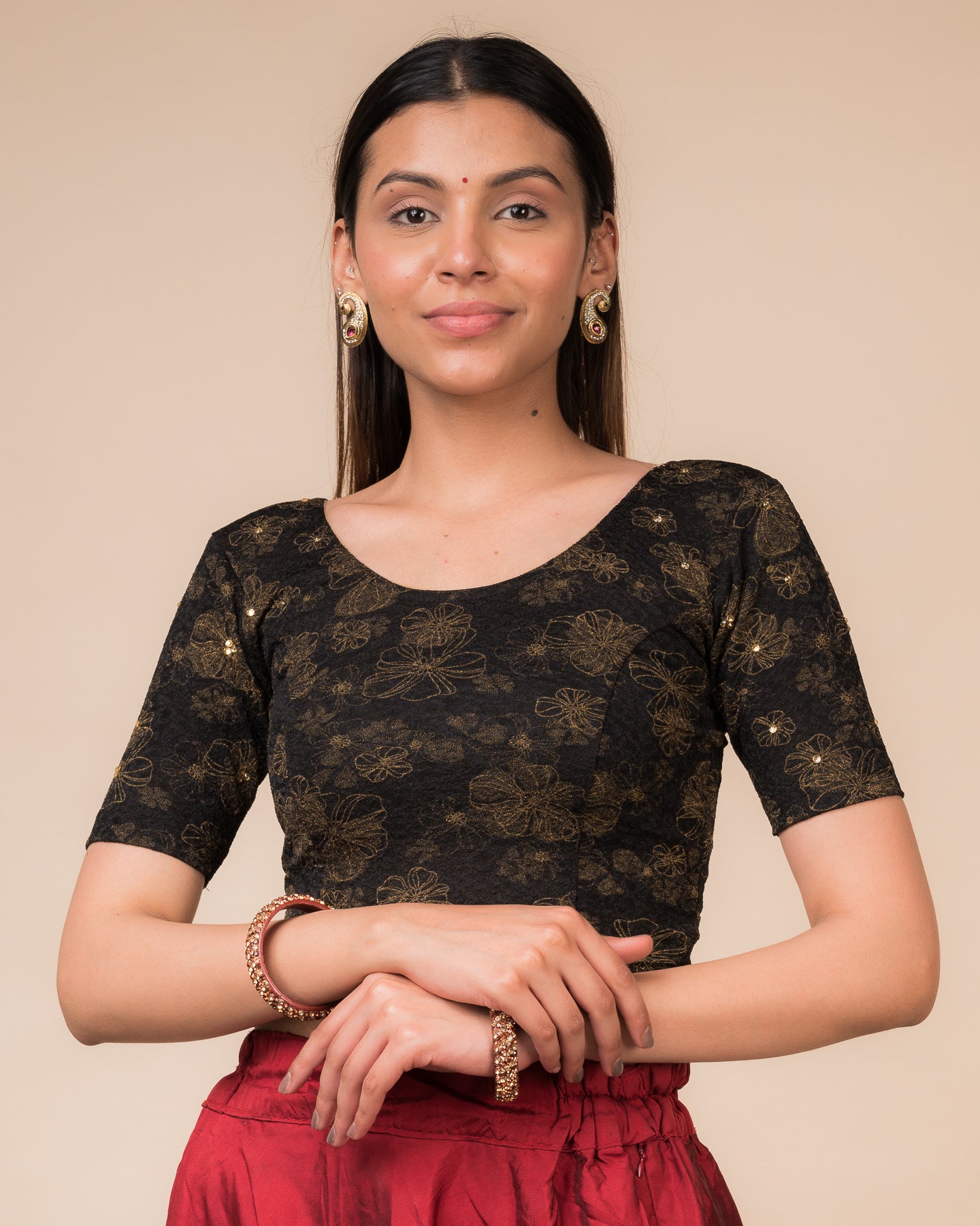 Model wearing a maroon foil and stone-embellished stretchable blouse with elbow sleeves and round neckline