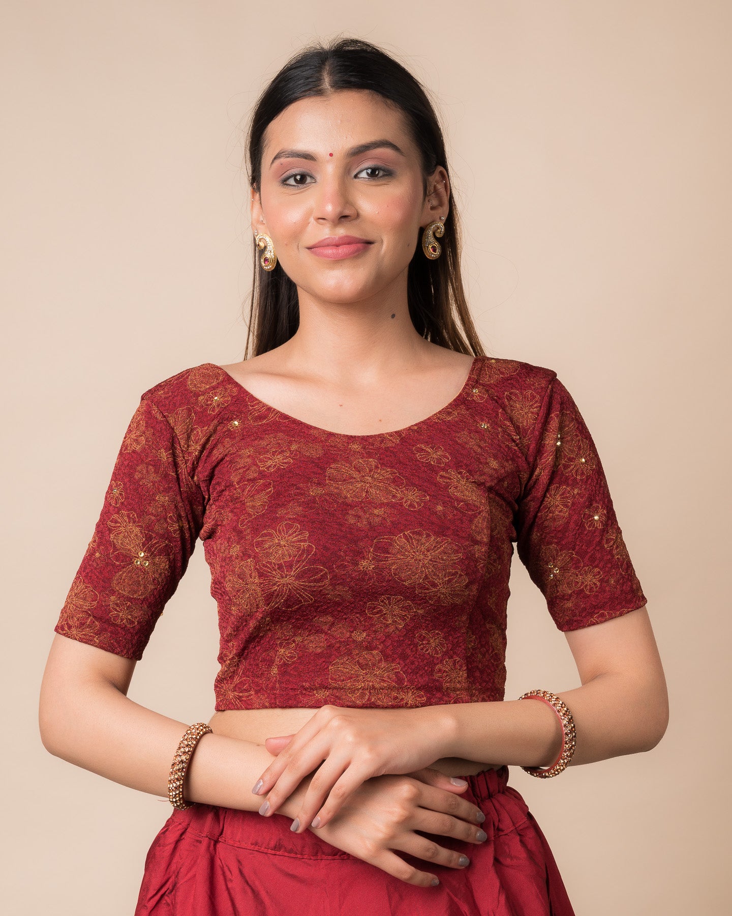 Model wearing a maroon foil and stone-embellished stretchable blouse with elbow sleeves and round neckline