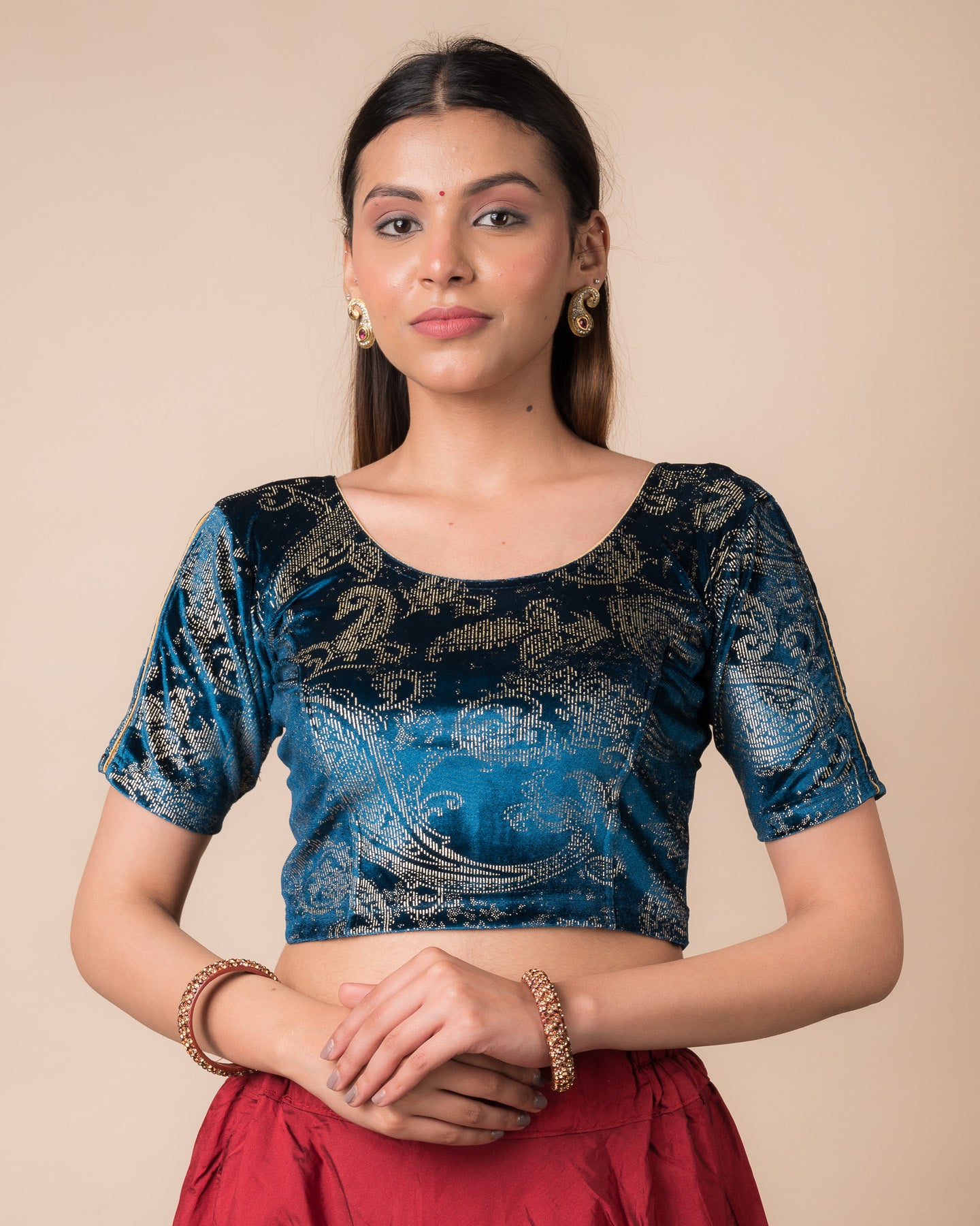 Model wearing a maroon velvet stretchable blouse with gold paisley prints, elbow sleeves, and round neckline.