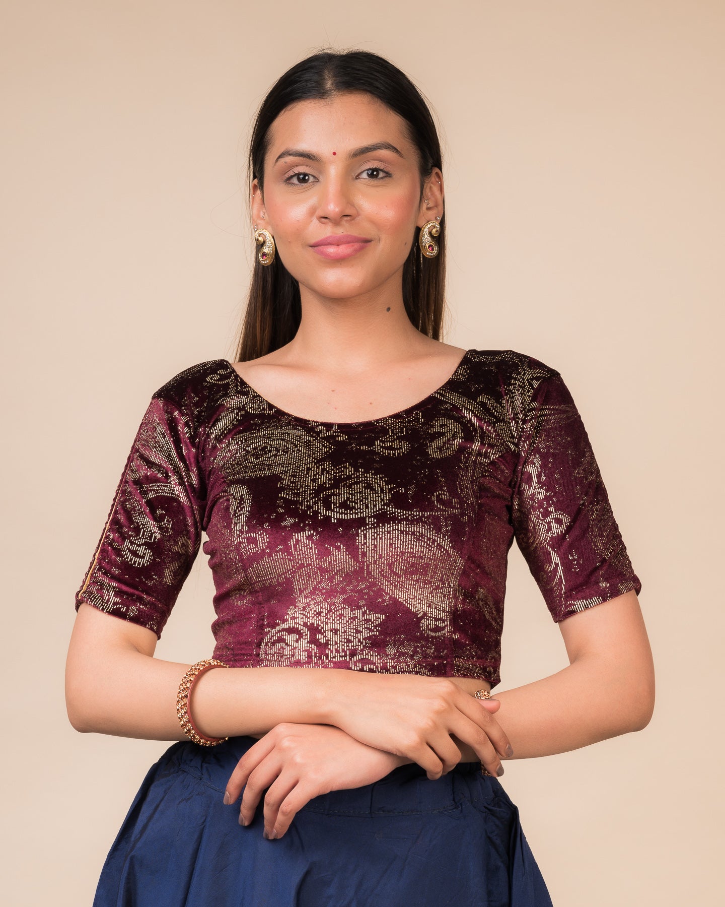 Model wearing a maroon velvet stretchable blouse with gold paisley prints, elbow sleeves, and round neckline.