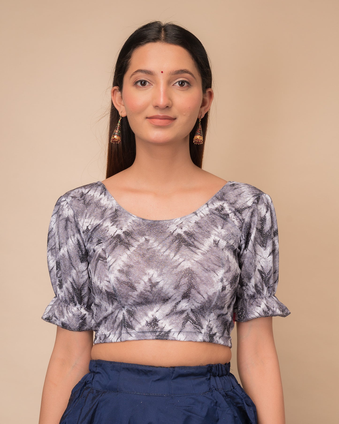 Model wearing a stretchable shibori blouse with glitter, sleek pleated elbow sleeves, and round neckline