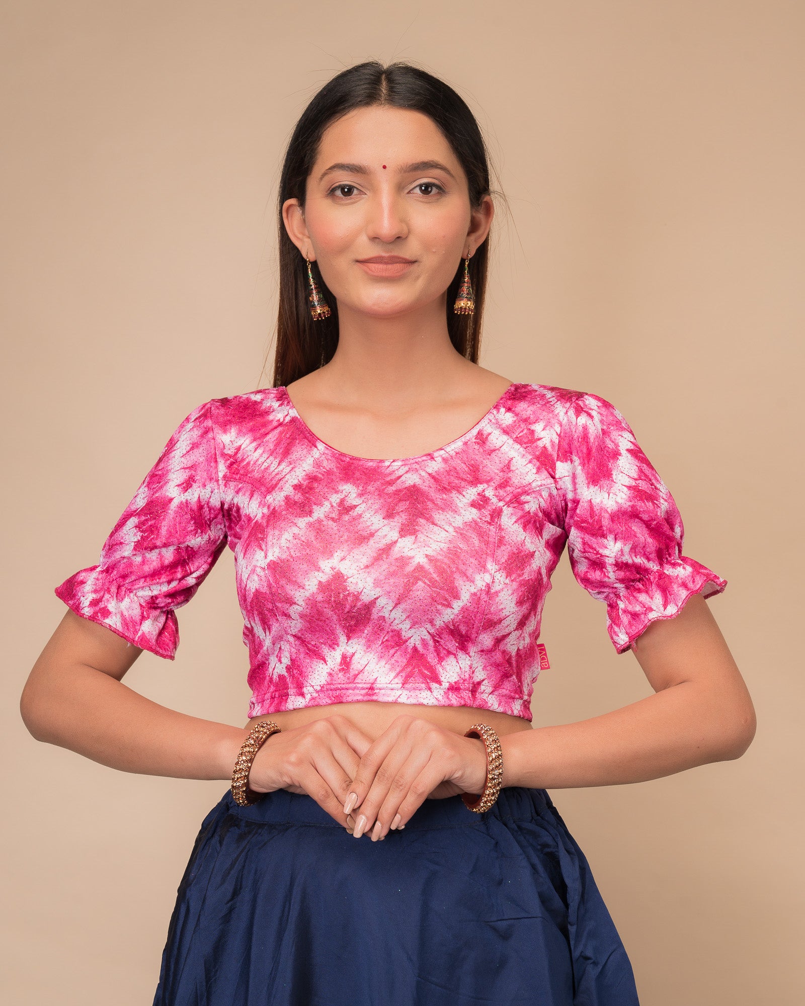 Model wearing a stretchable shibori blouse with glitter, sleek pleated elbow sleeves, and round neckline