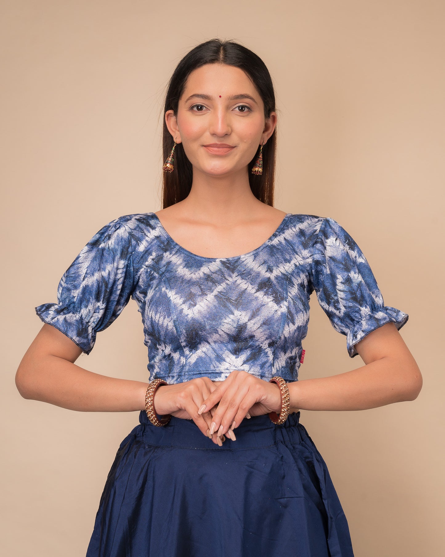 Model wearing a stretchable shibori blouse with glitter, sleek pleated elbow sleeves, and round neckline