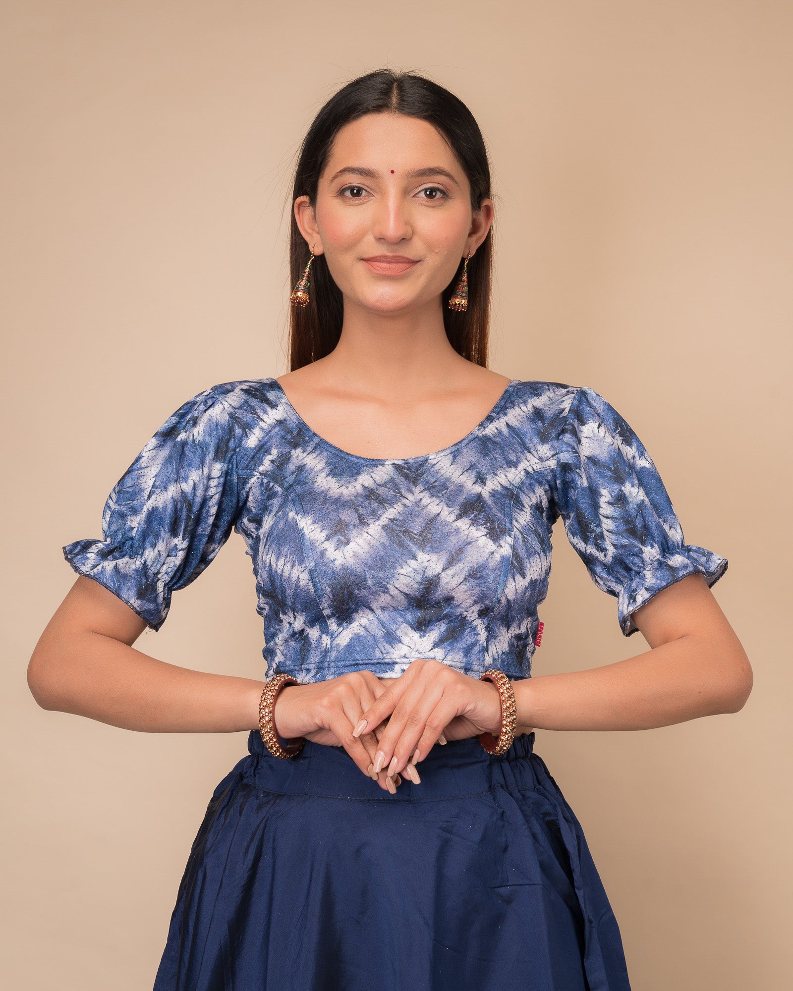 Model wearing a stretchable shibori blouse with glitter, sleek pleated elbow sleeves, and round neckline