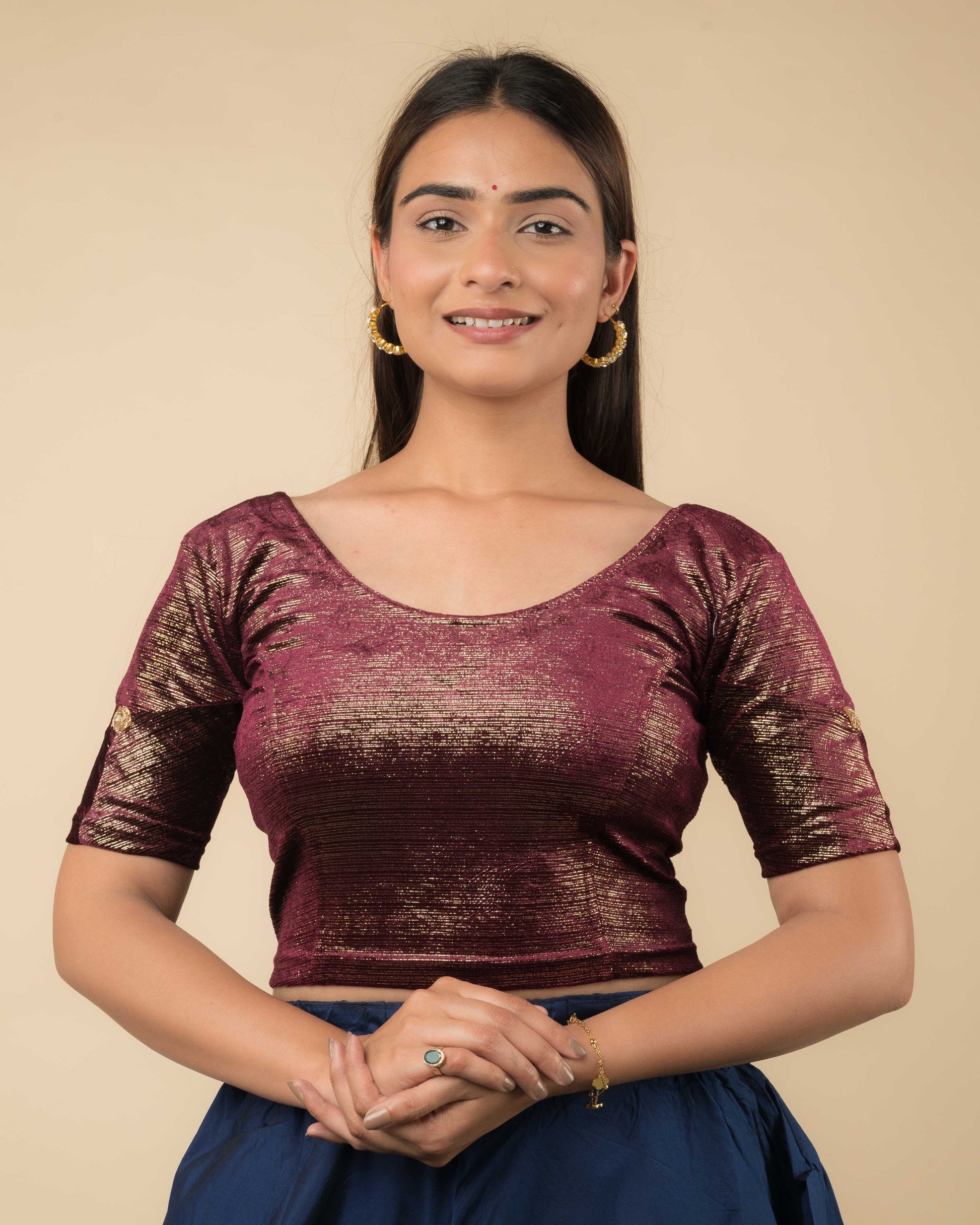 Model wearing a maroon velvet blouse with gold buti and stripes, elbow sleeves, and round neckline