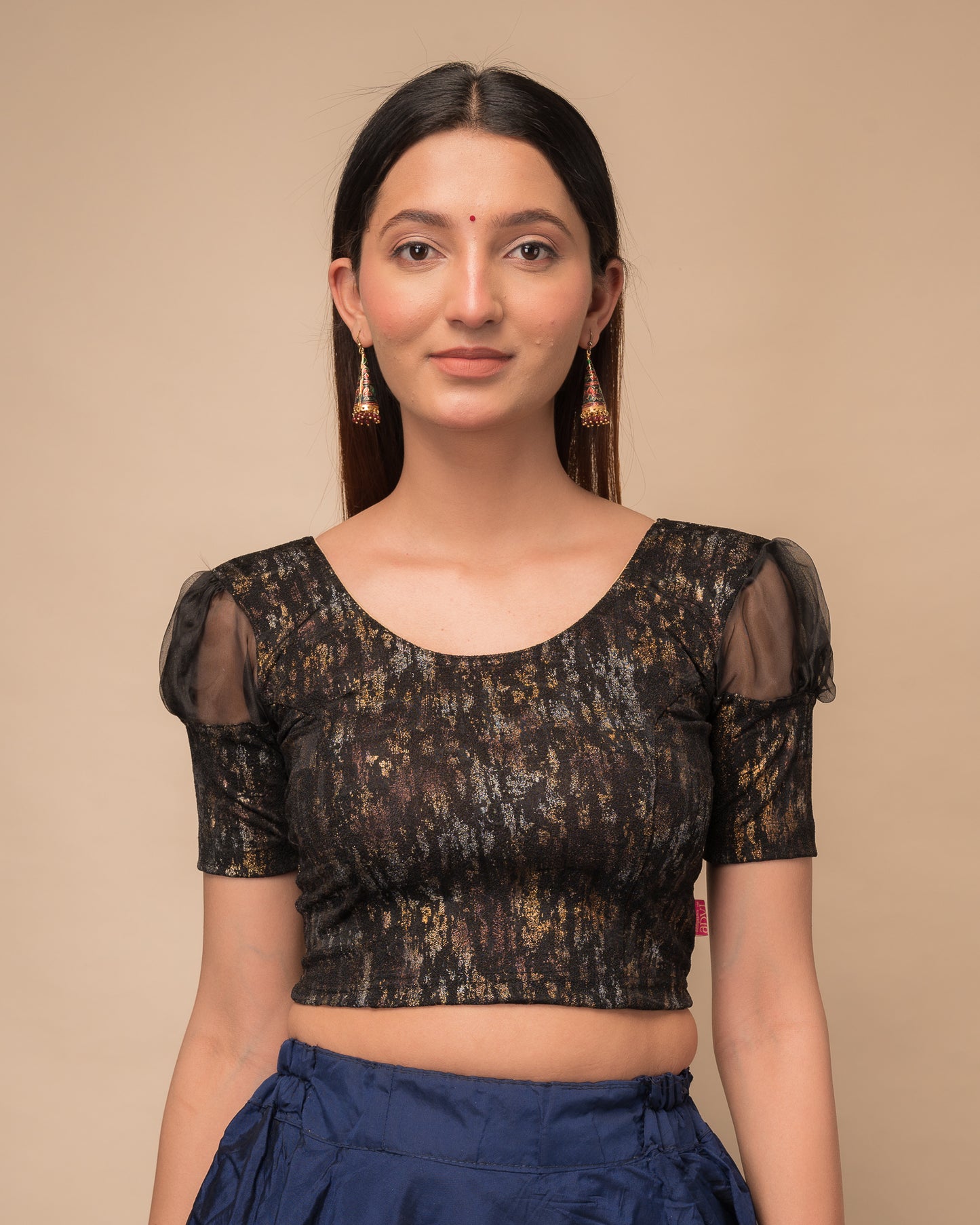 Model wearing a stretchable foil-textured blouse with sheer puff sleeves and round neckline