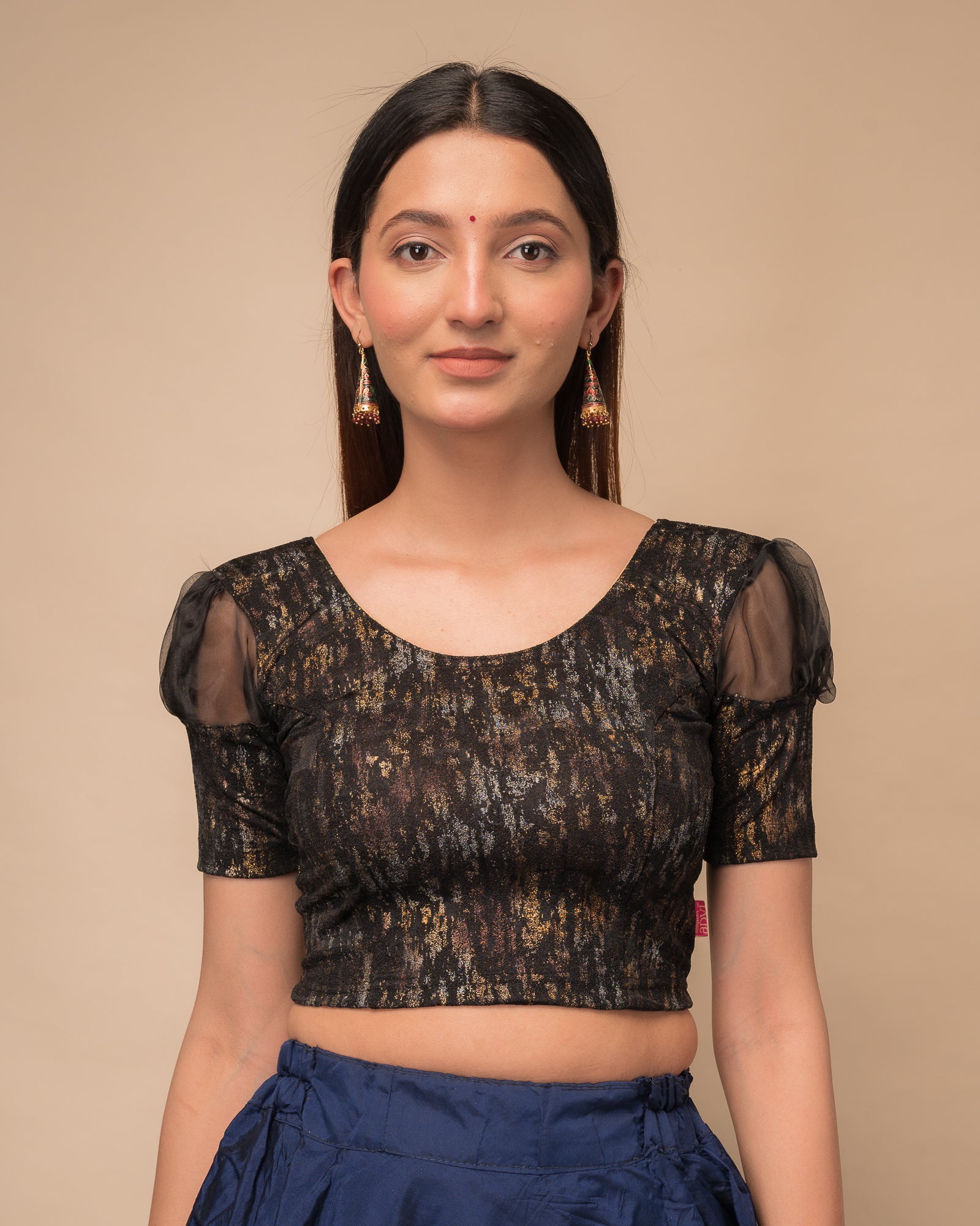 Model wearing a stretchable foil-textured blouse with sheer puff sleeves and round neckline