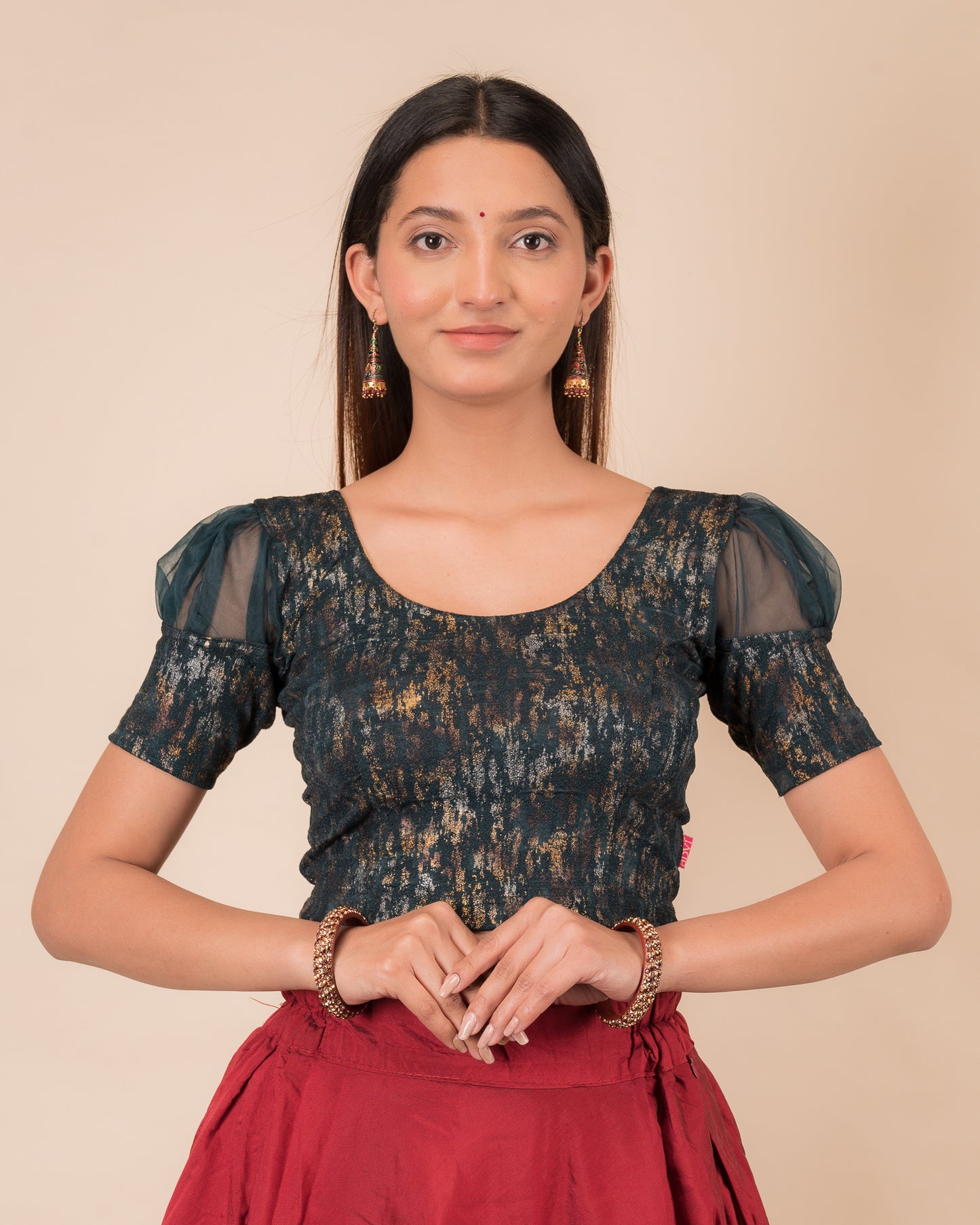 Model wearing a stretchable foil-textured blouse with sheer puff sleeves and round neckline
