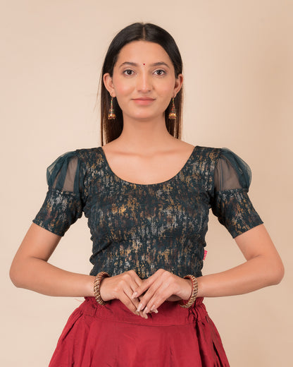 Model wearing a stretchable foil-textured blouse with sheer puff sleeves and round neckline