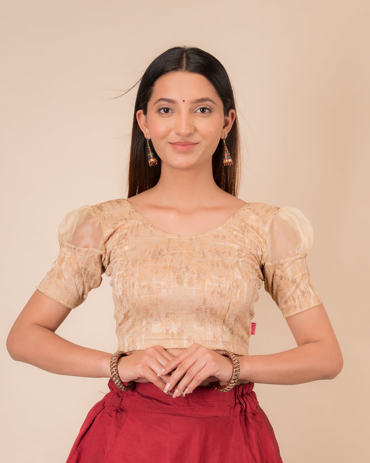 Model wearing a stretchable foil-textured blouse with sheer puff sleeves and round neckline